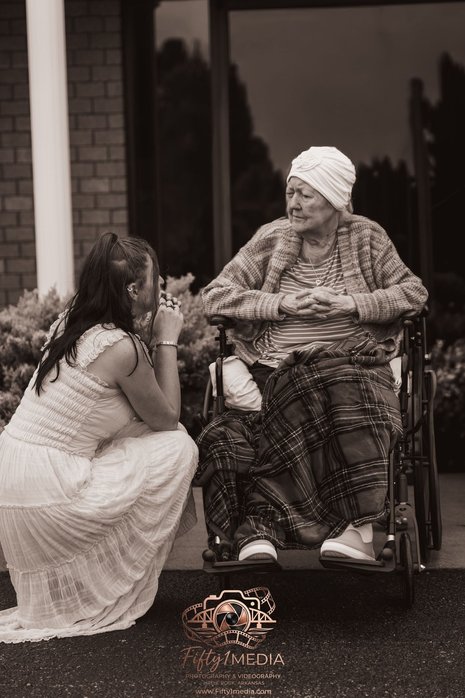 Black and white documentary-style photography of a woman speaking with a senior family member in a wheelchair.