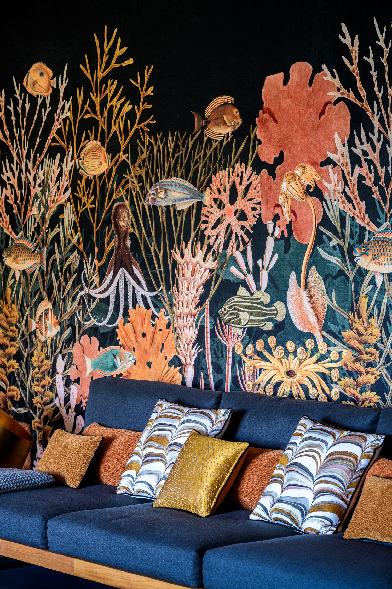 Papier peint panoramique décoratif corail et poissons sur fond noir dans un salon, détail de design d'intérieur.