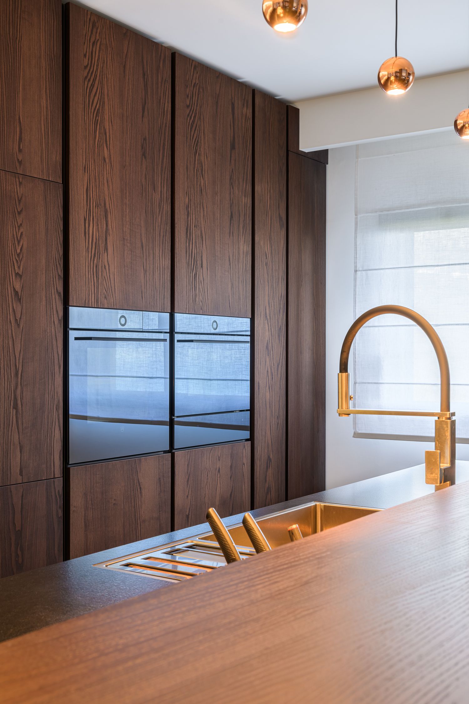 Détail de cuisine avec menuiserie en bois foncé et robinetterie dorée de luxe, photographie d'agencement.