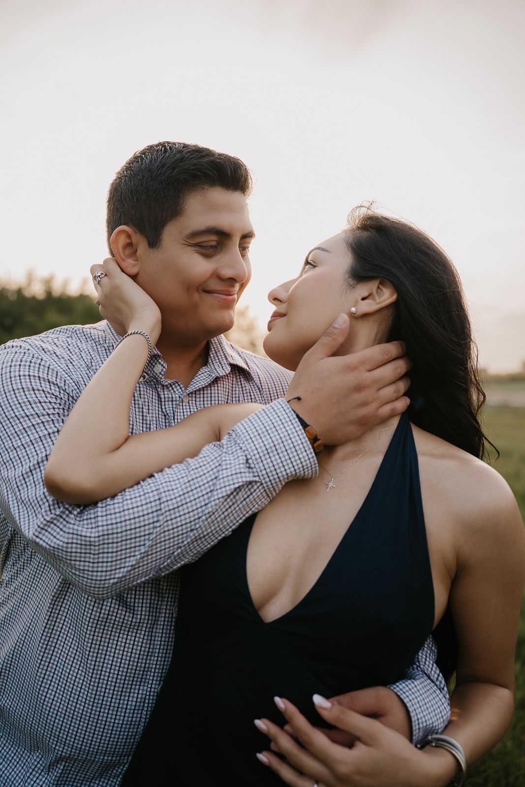 Romantic couple tenderly holding each other's faces during golden hour outdoor portrait.