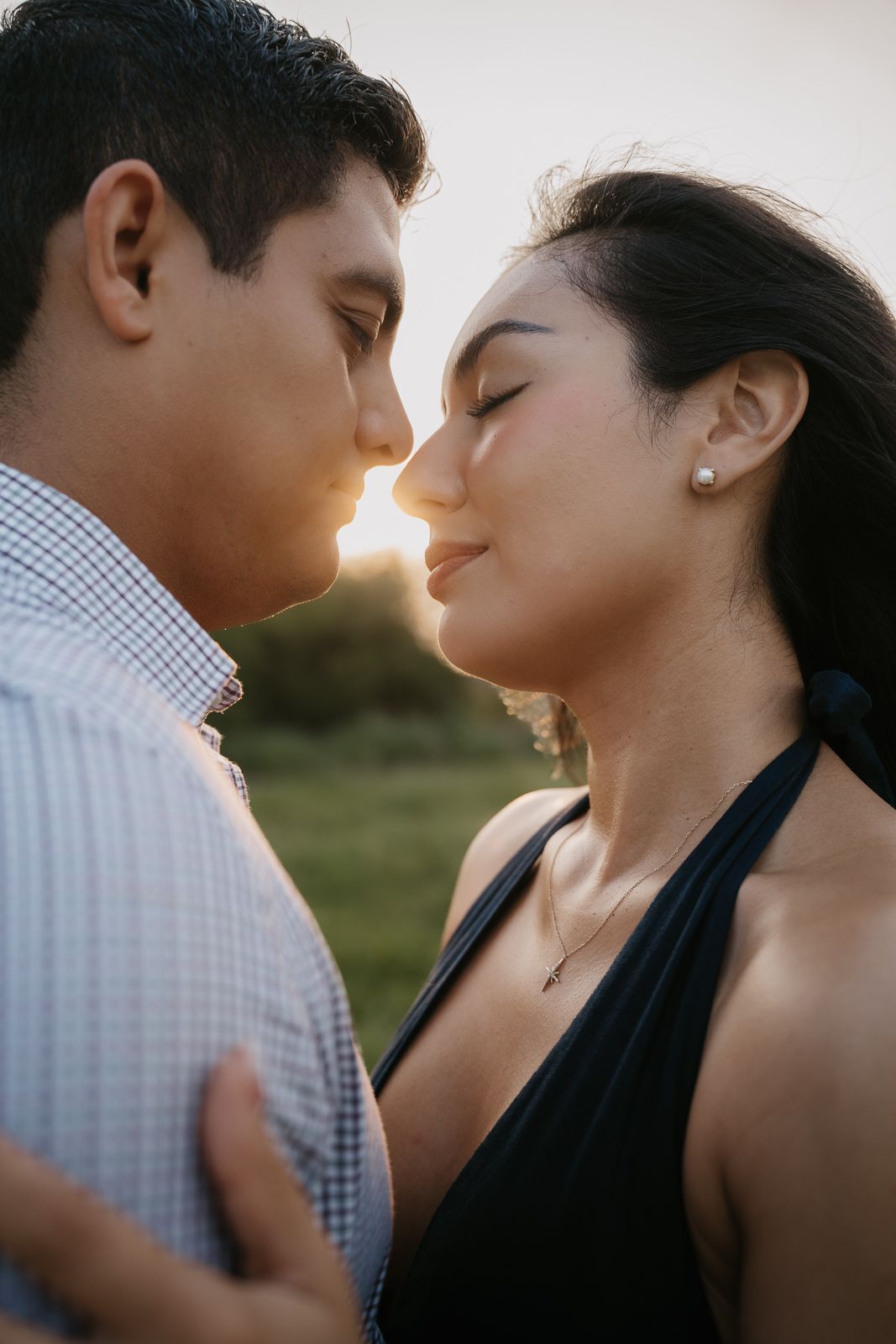 Couple sharing a romantic almost-kiss at golden hour sunset outdoors.