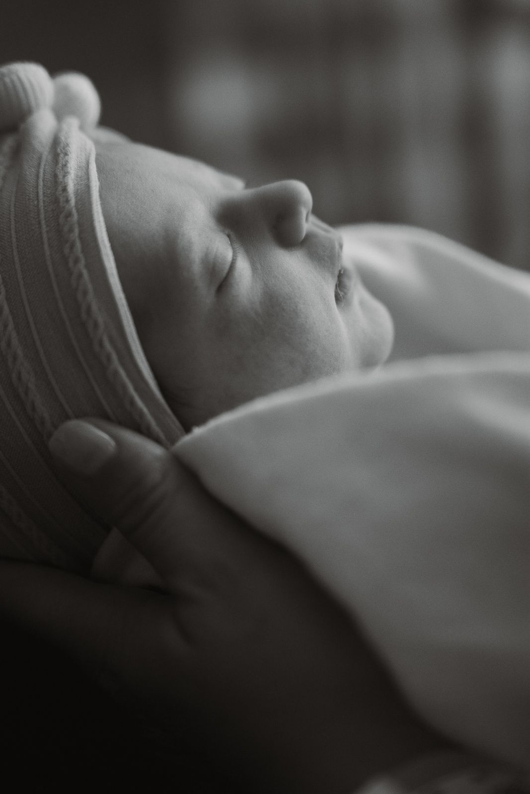 Peaceful newborn baby sleeping in black and white portrait photography.