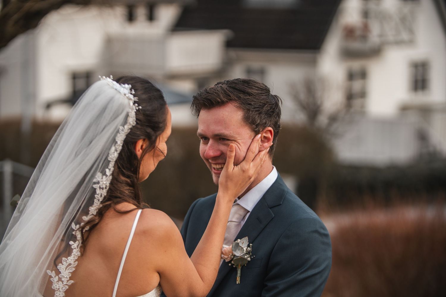 Bride tenderly touching grooms face as they share a joyful moment on their wedding day.