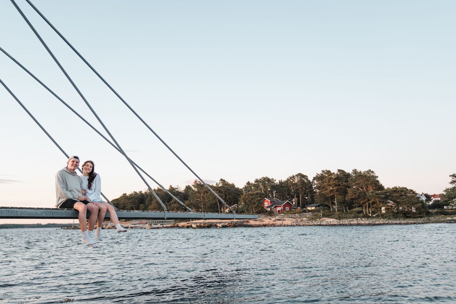 Happy couple sitting together on dock edge at peaceful waterfront during sunset.