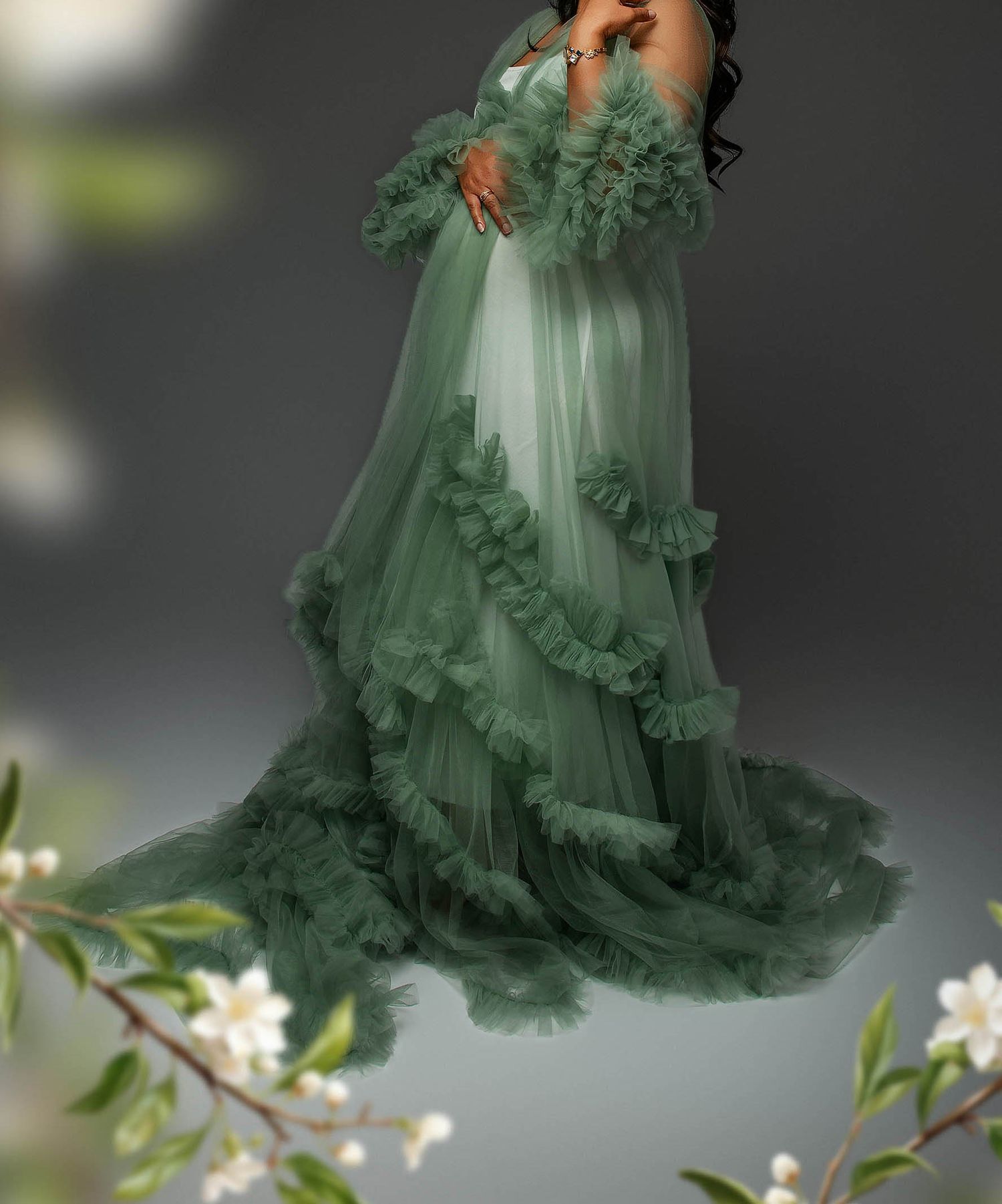Elegant green tulle maternity gown with ruffled layers and long sleeves, perfect for a photoshoot.