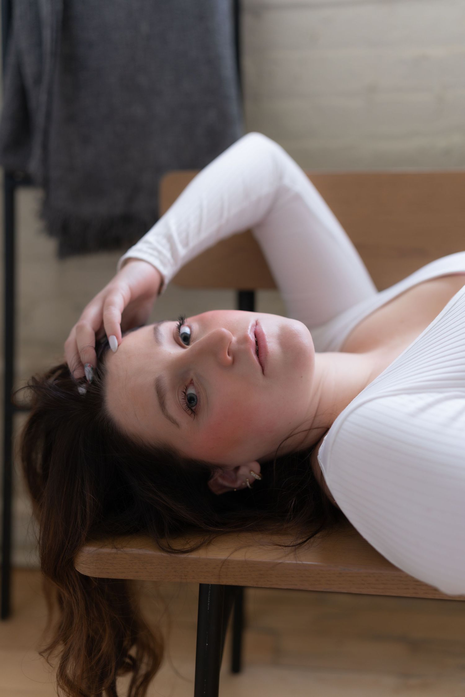 A series of artistic portraits showing a person in a white top lying on a wooden surface in different relaxed poses.