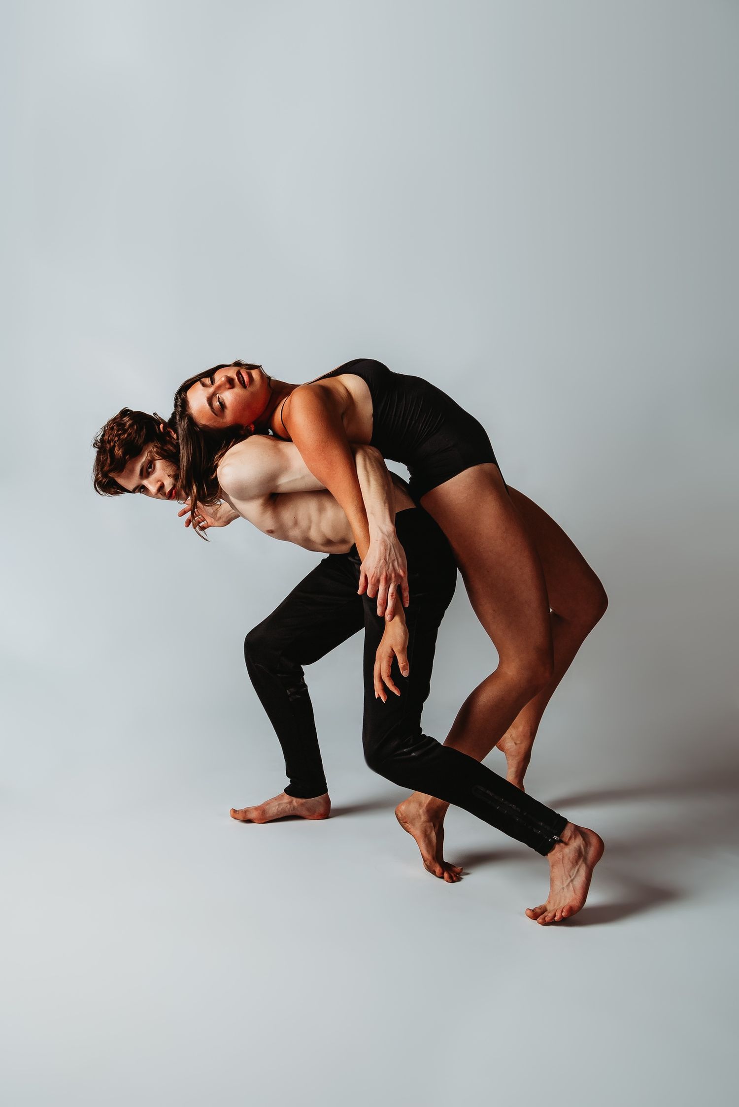 Two dancers in black attire performing intimate contemporary duet pose.