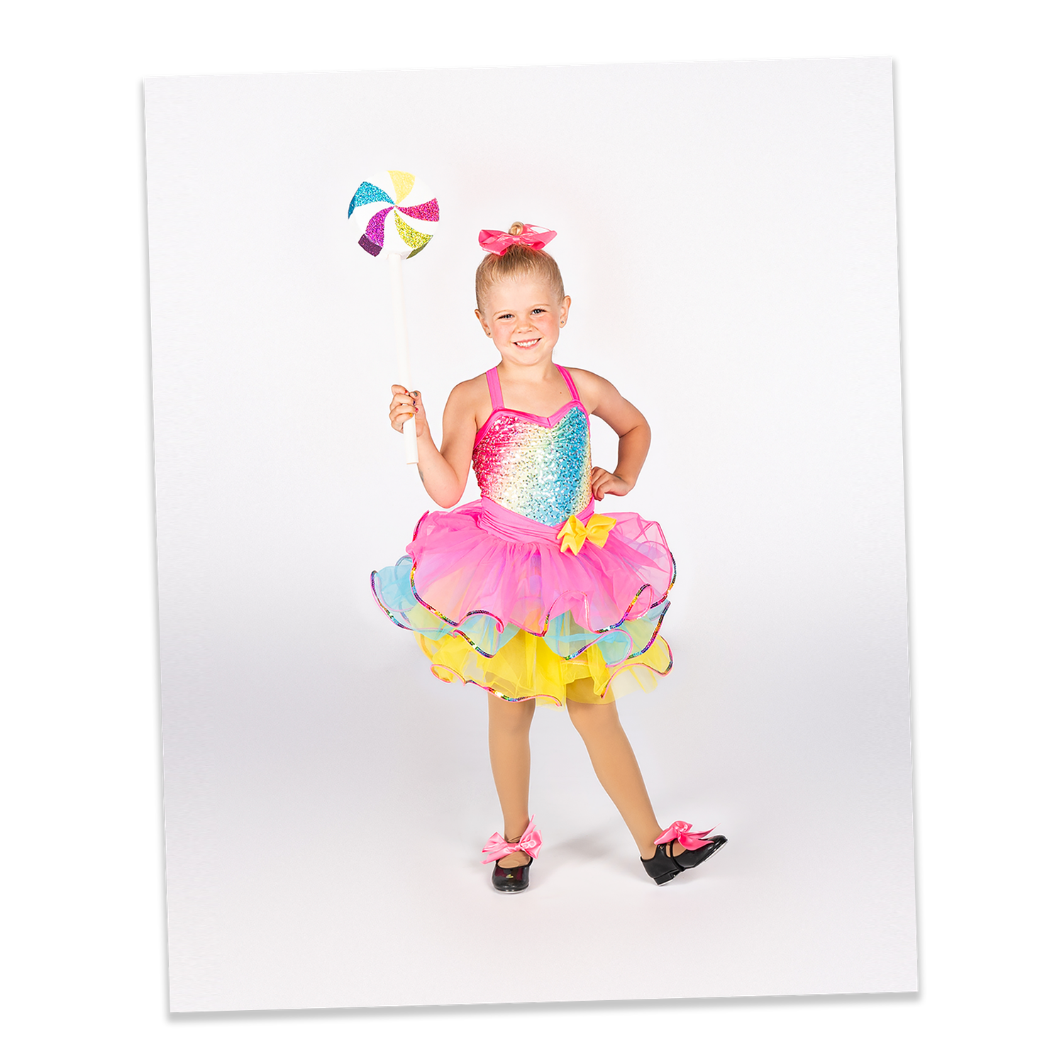 Young dancer in colorful tutu dress performs with beach ball against white studio background.