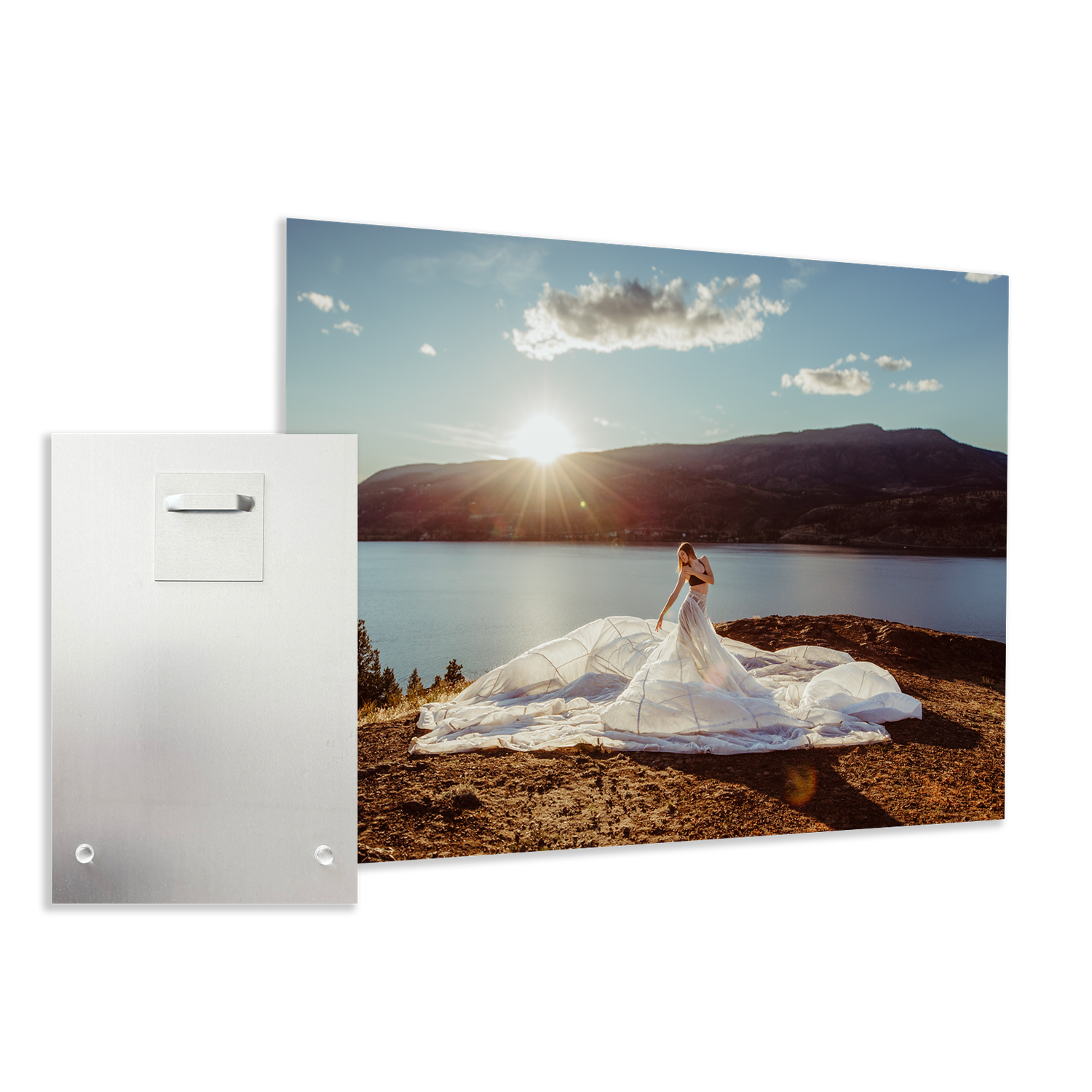 A wedding dress billows dramatically on a mountain overlook at sunset, with a scenic lake and mountains in the background.