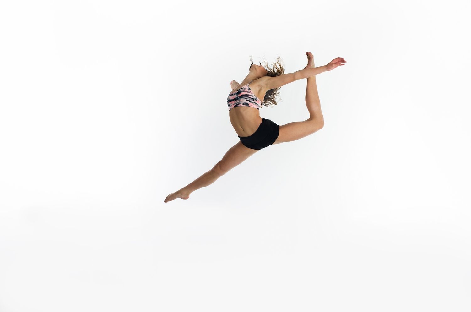 Dancer in black and white outfit performs graceful leap with extended limbs.