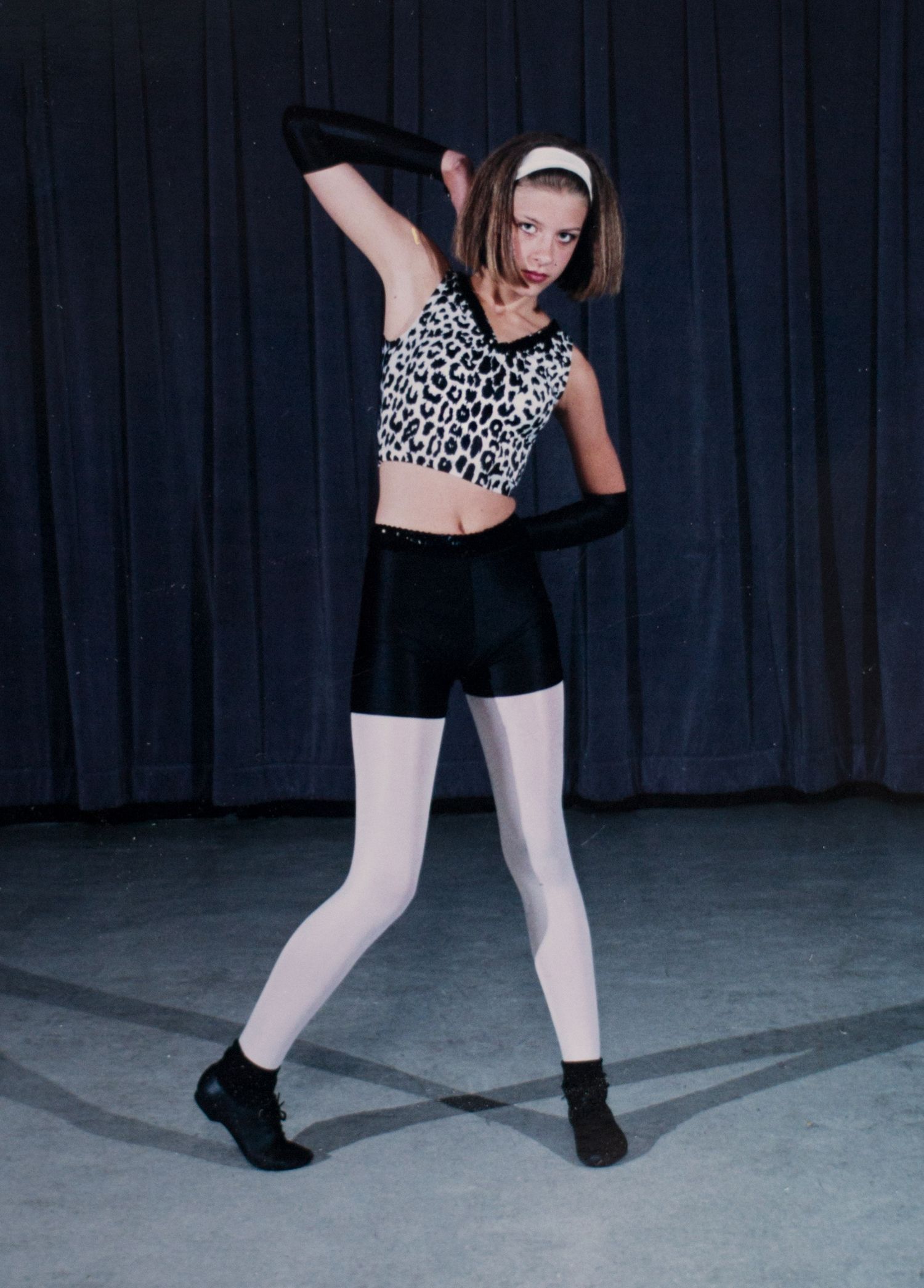 Dancer in animal print top and black shorts strikes dynamic pose on stage.