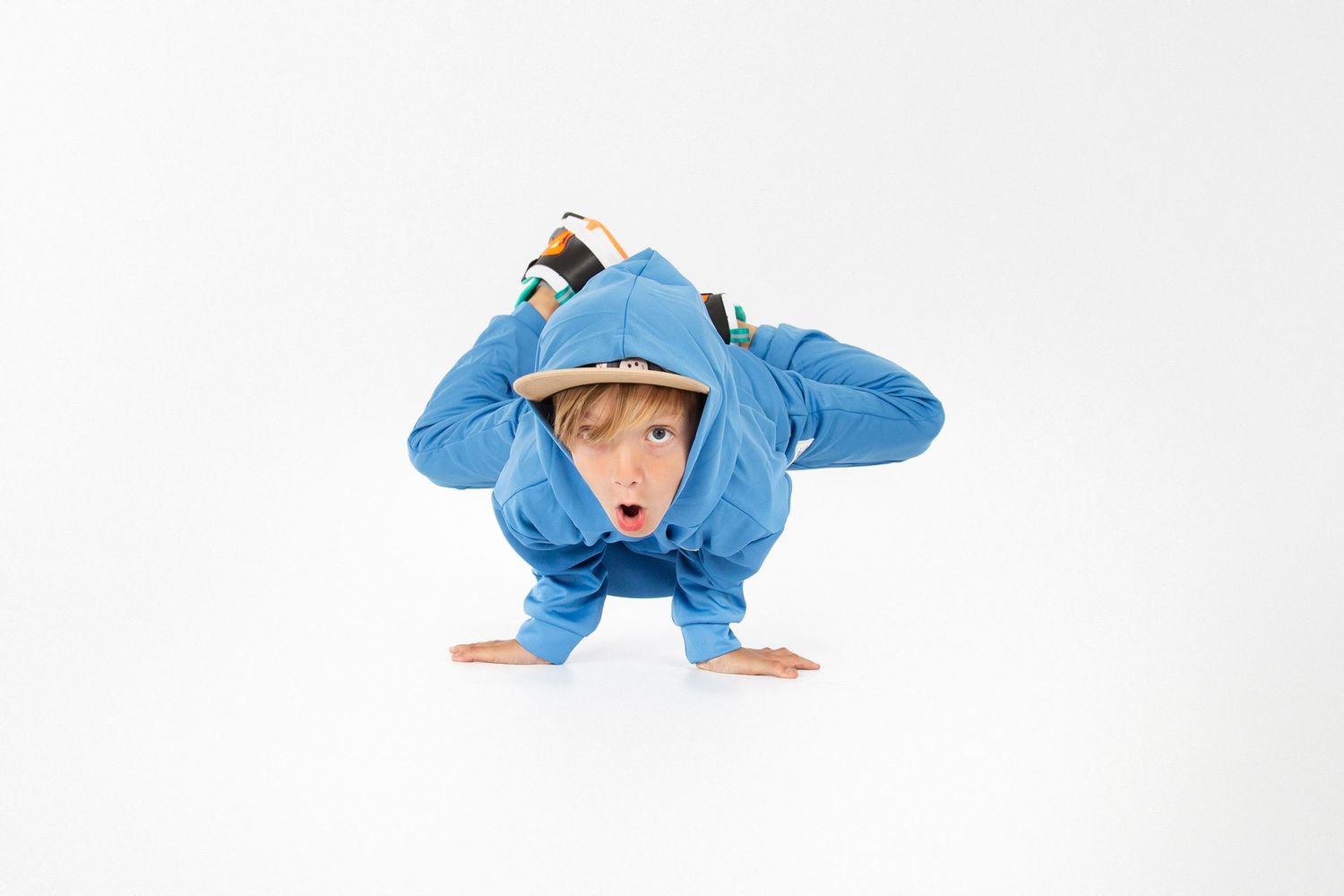 Person in bright blue athletic wear performs a breakdancing move on white background.