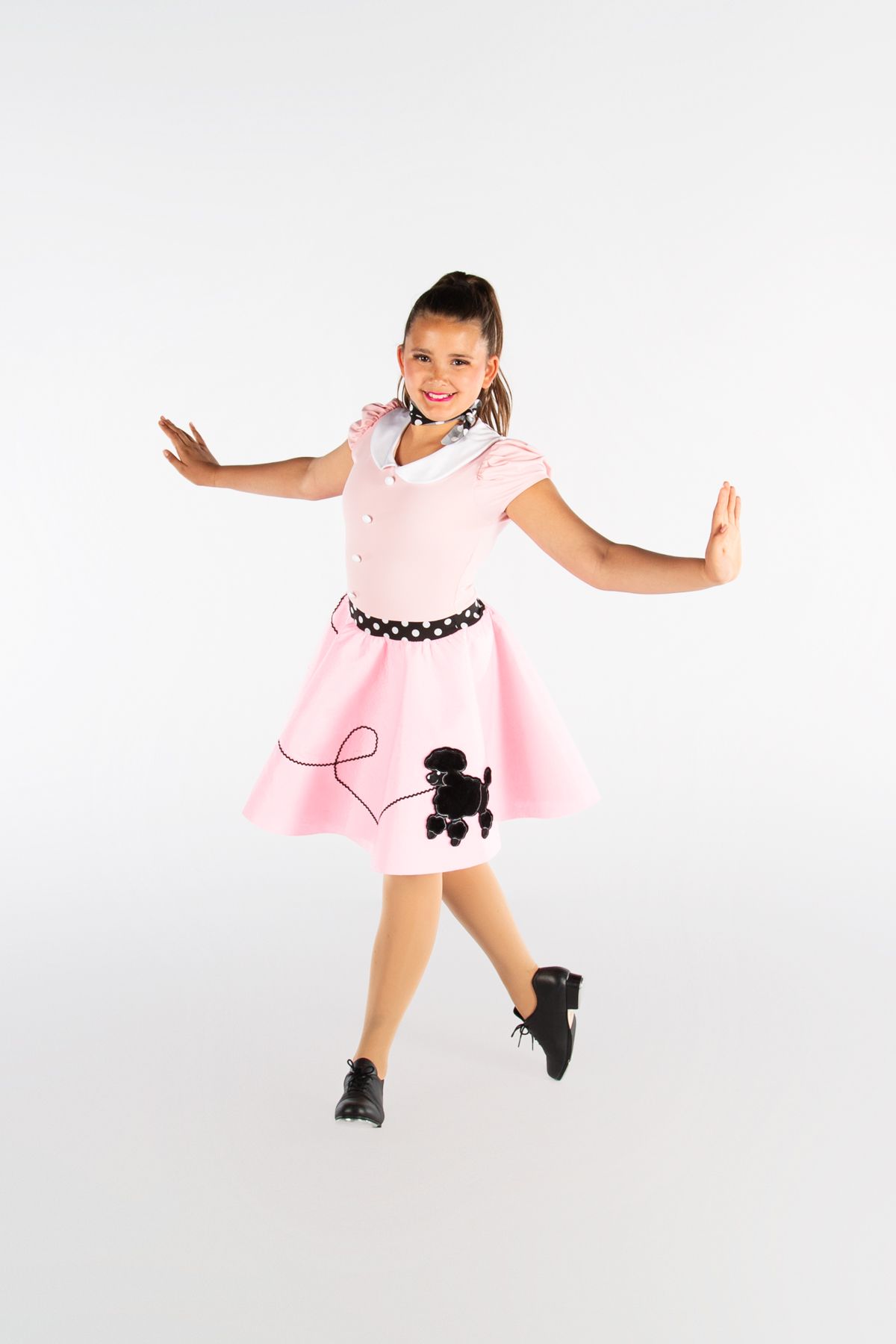 Dancer in pink poodle skirt dress performing retro-inspired dance pose on white background.