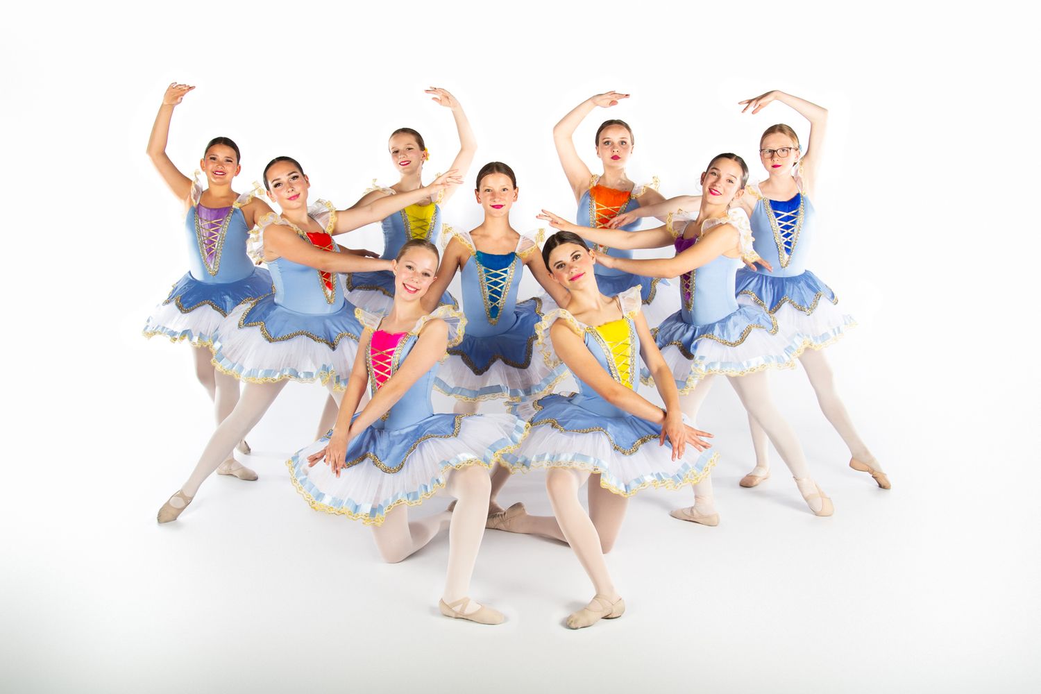 Ballet dancers in colorful leotards strike dynamic poses in a group formation against a white background.