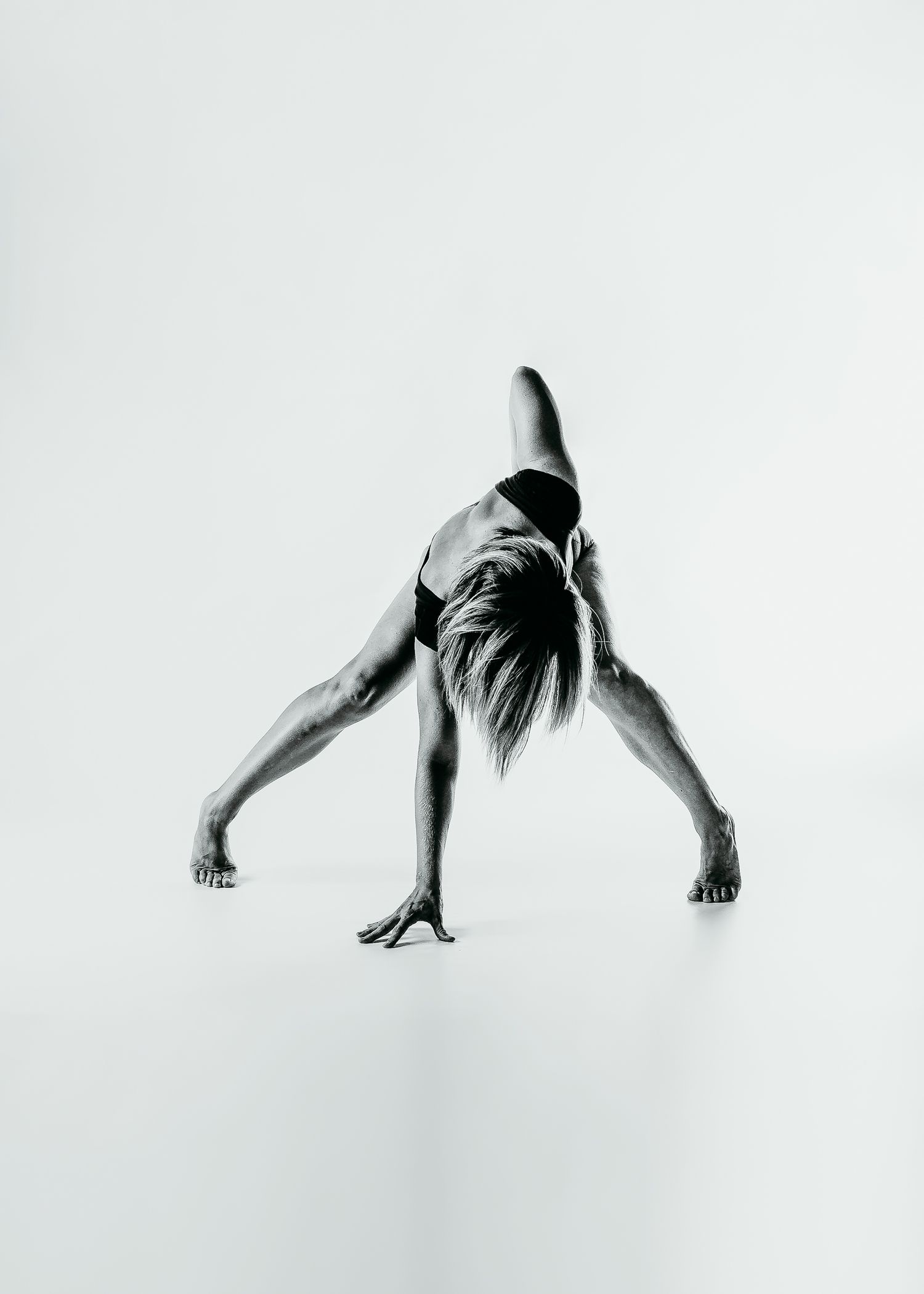 Artistic black and white photo of dancer in inverted pose with dramatic lines and form.