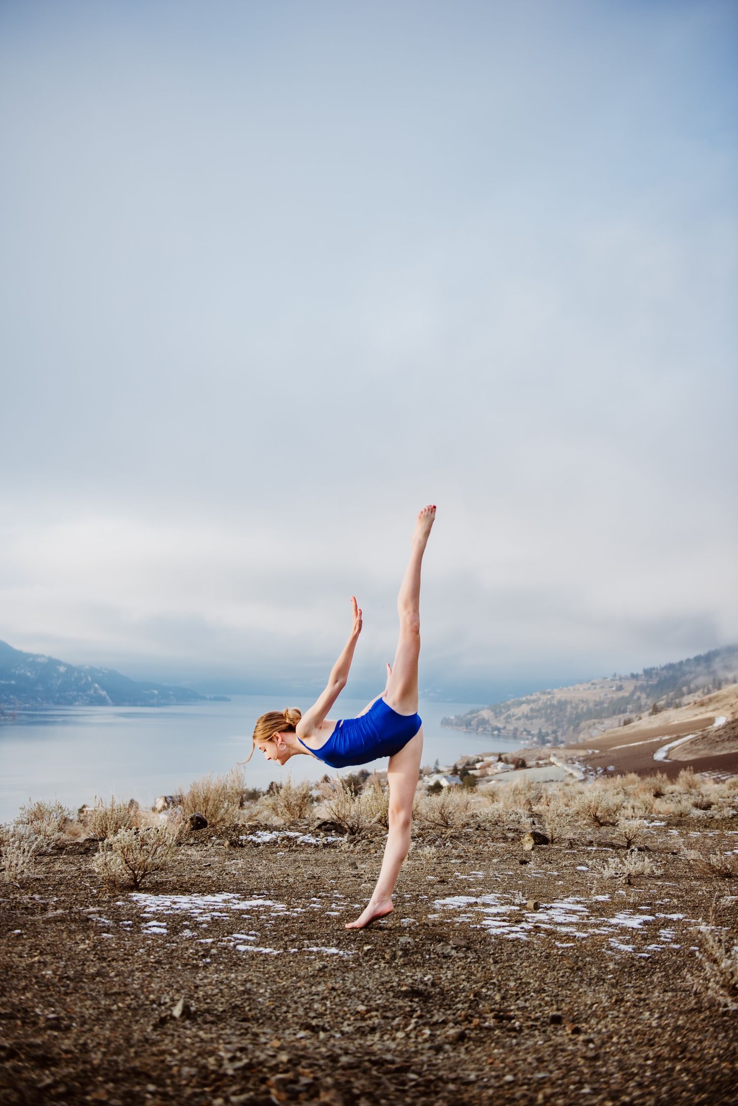 Graceful dance movement captured against a misty lake and mountain landscape.