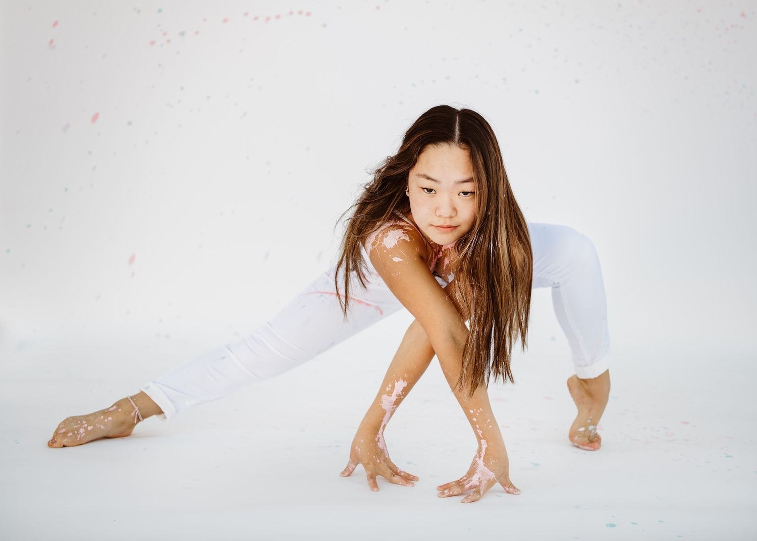 Modern dancer in white performs contemporary movement on light background.