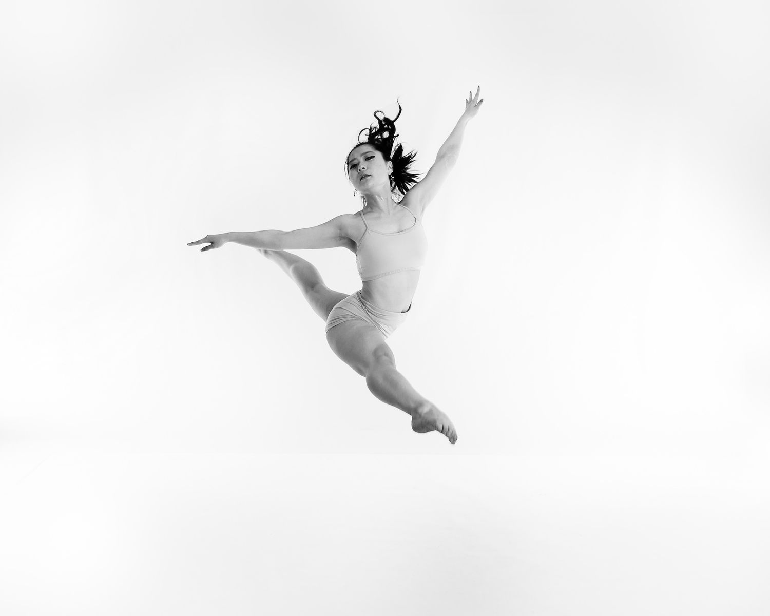 Graceful dancer leaps through the air in a dynamic black and white performance shot.