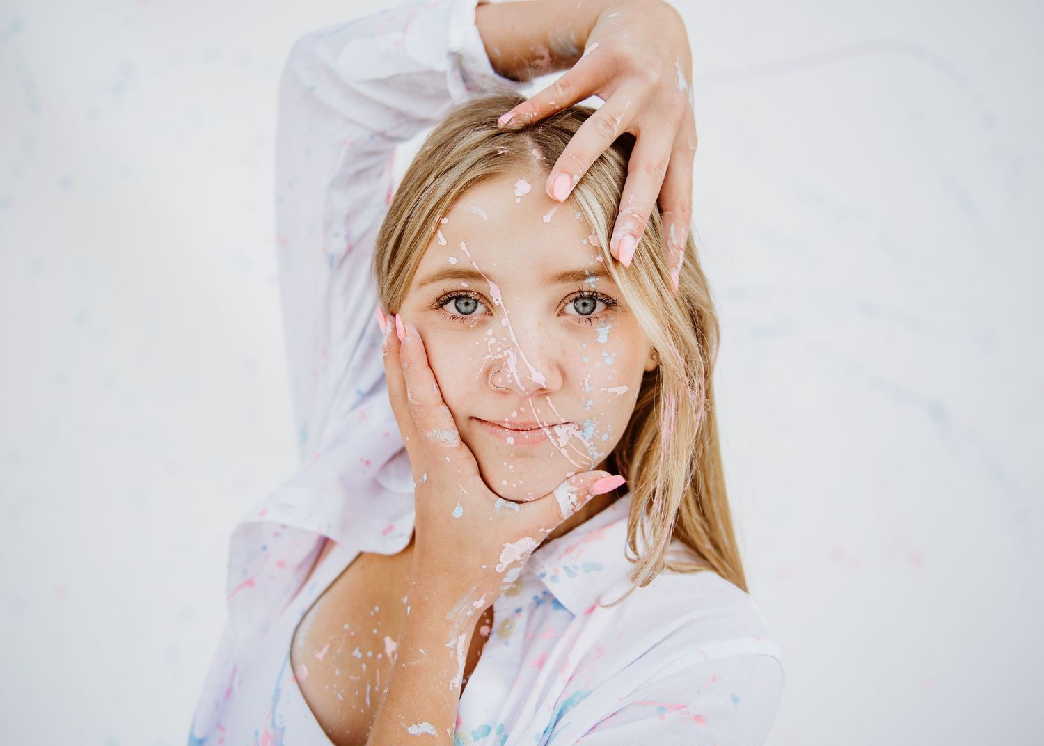 Soft portrait photo against white background showing gentle hand gestures and long blonde hair.