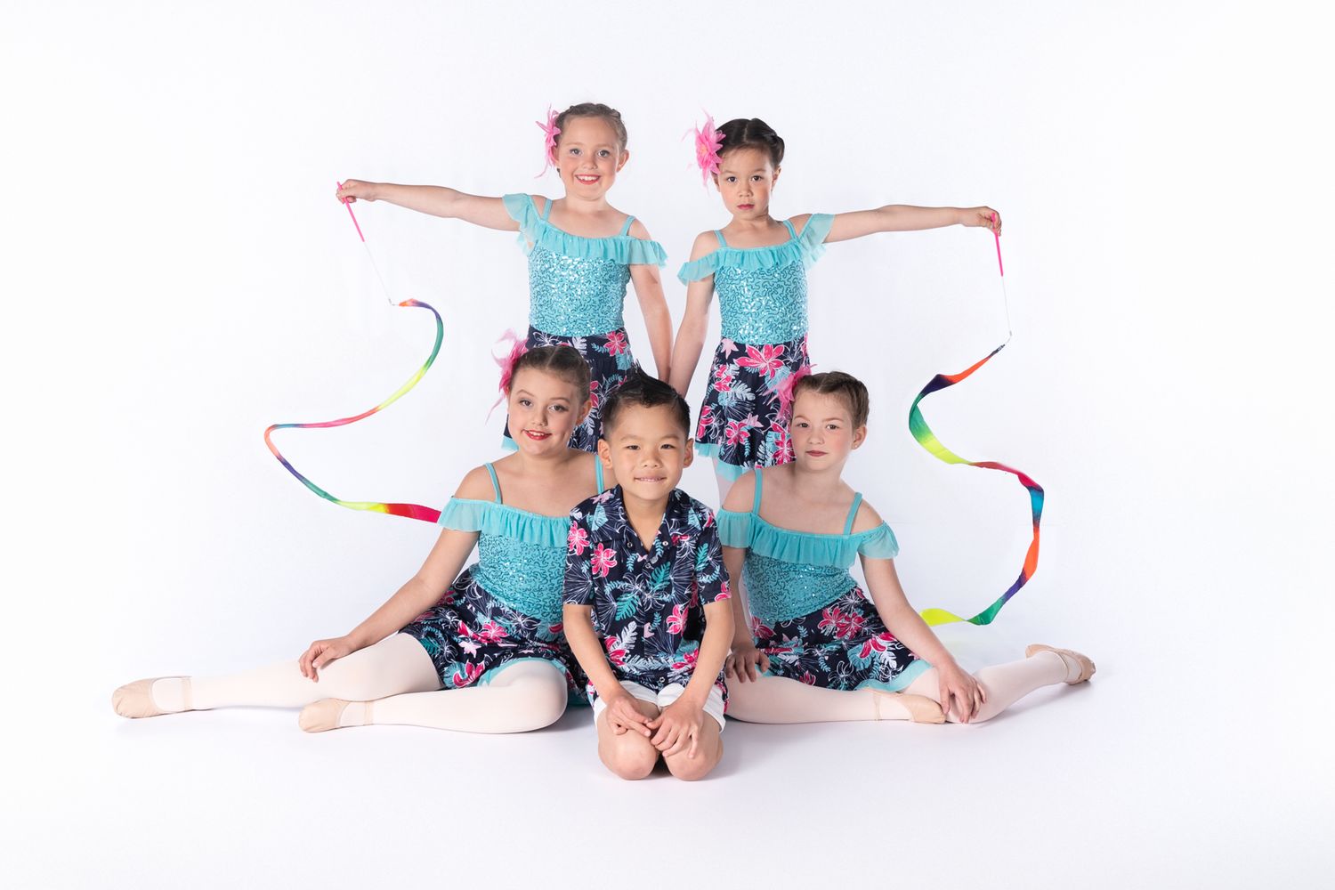Five dancers in matching turquoise and floral outfits pose artistically against white background.