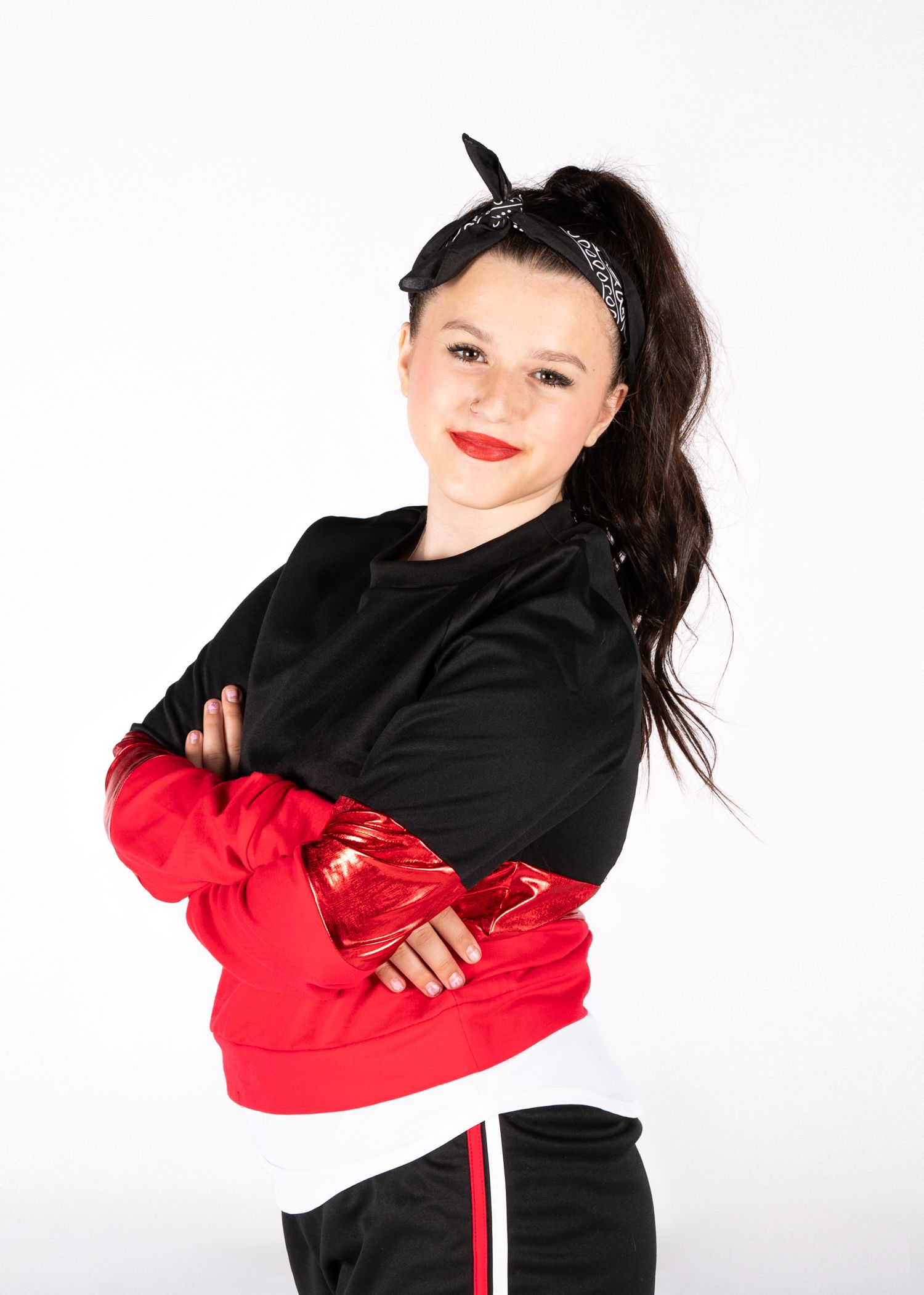 A person in a black and red athletic outfit with a patterned headband poses confidently against a white backdrop.