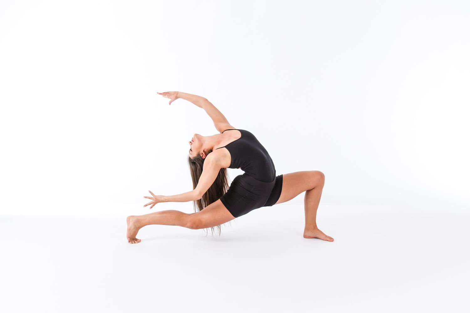 Dancer in black performs modern dance pose with fluid arm movements against white backdrop.
