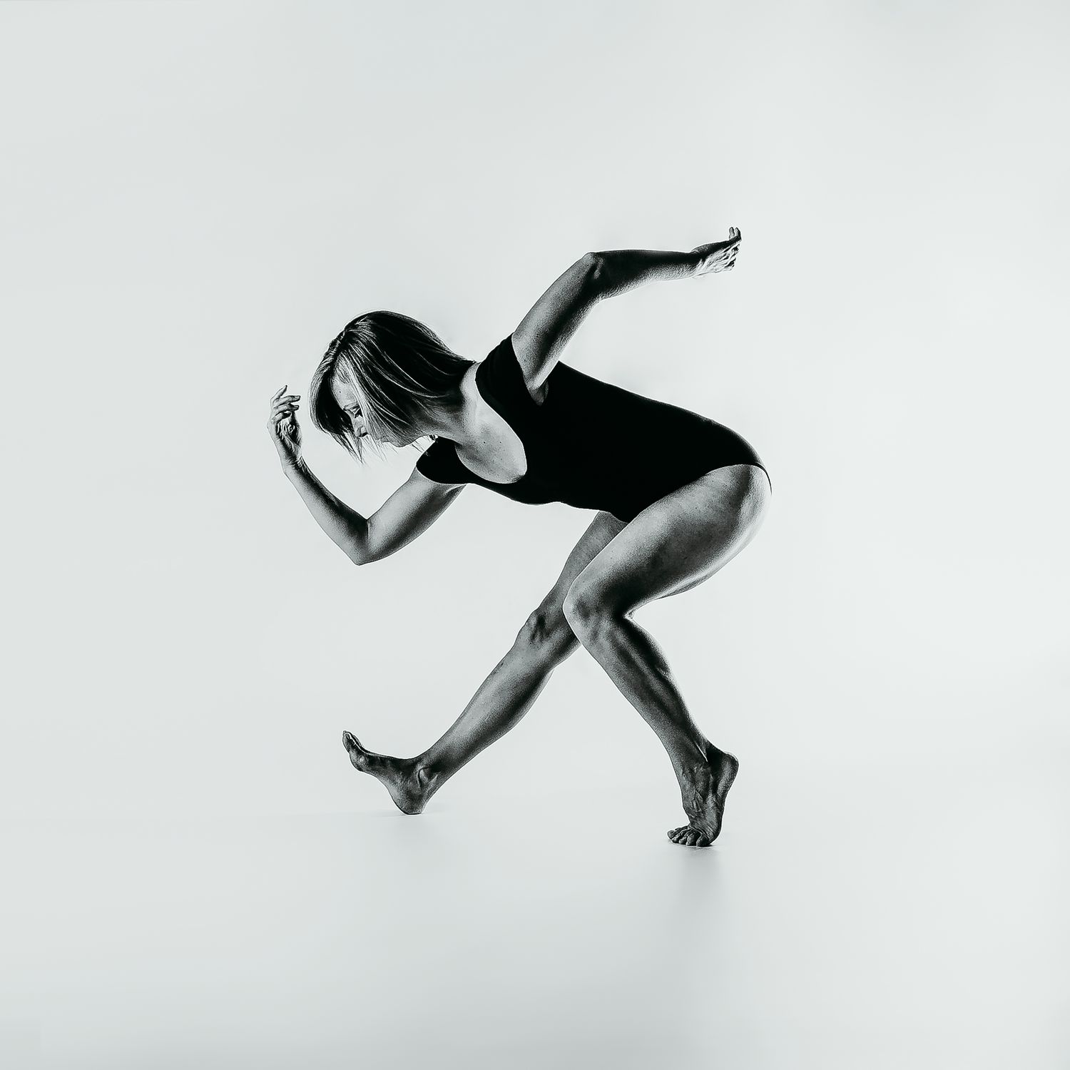 Artistic black and white photo of dancer in dynamic crouching position.
