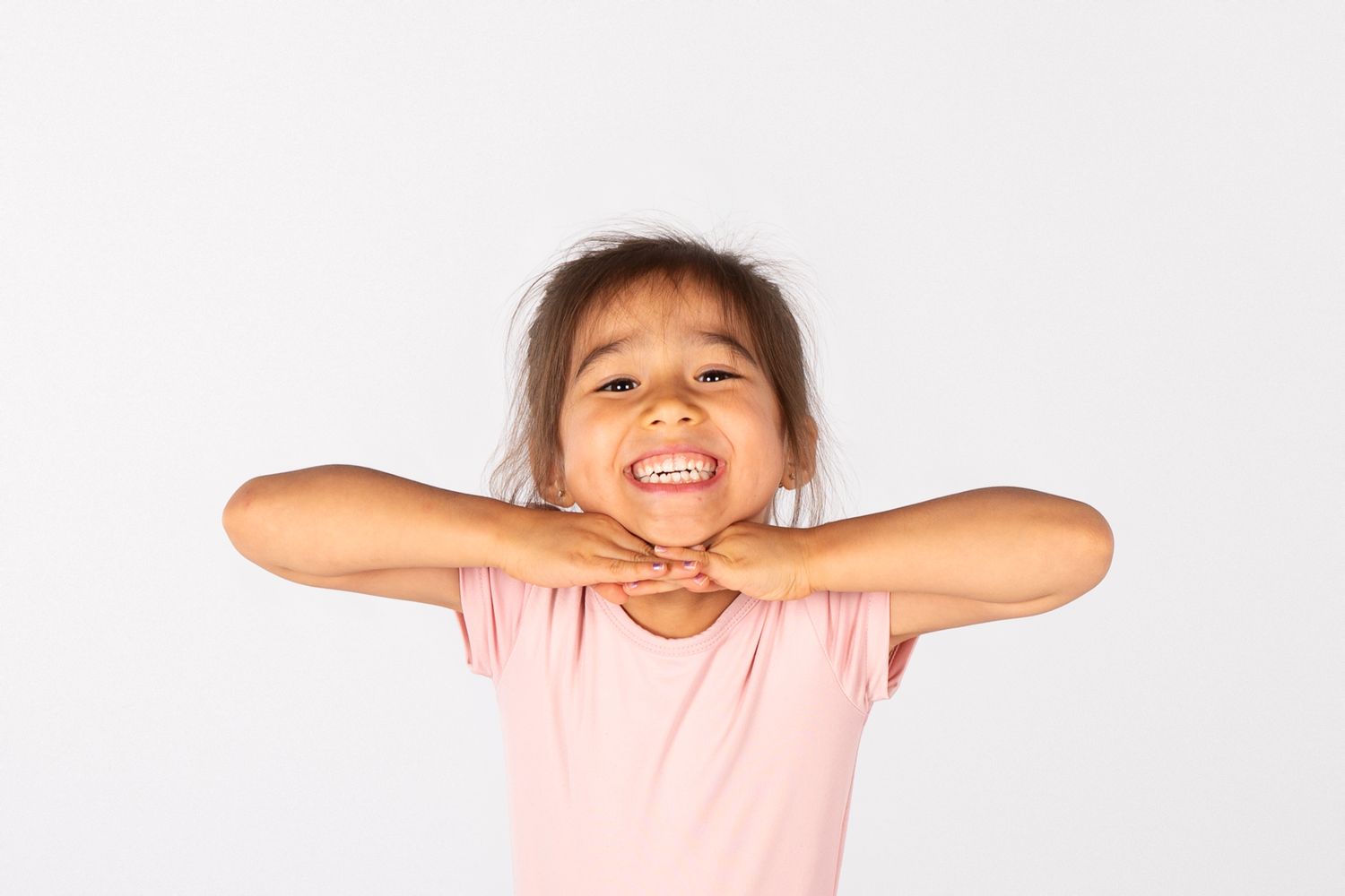 Young dancer in pink shirt expressing joy with animated facial expression.