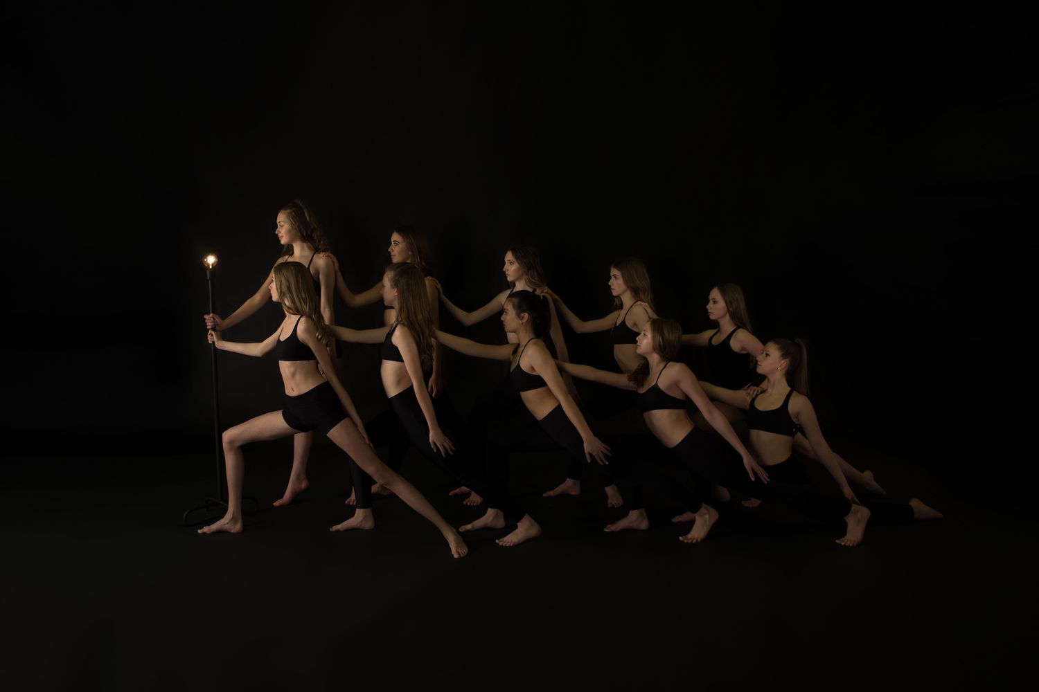 Multiple exposure photo captures dancer in black leotard moving in sequence against dark background.