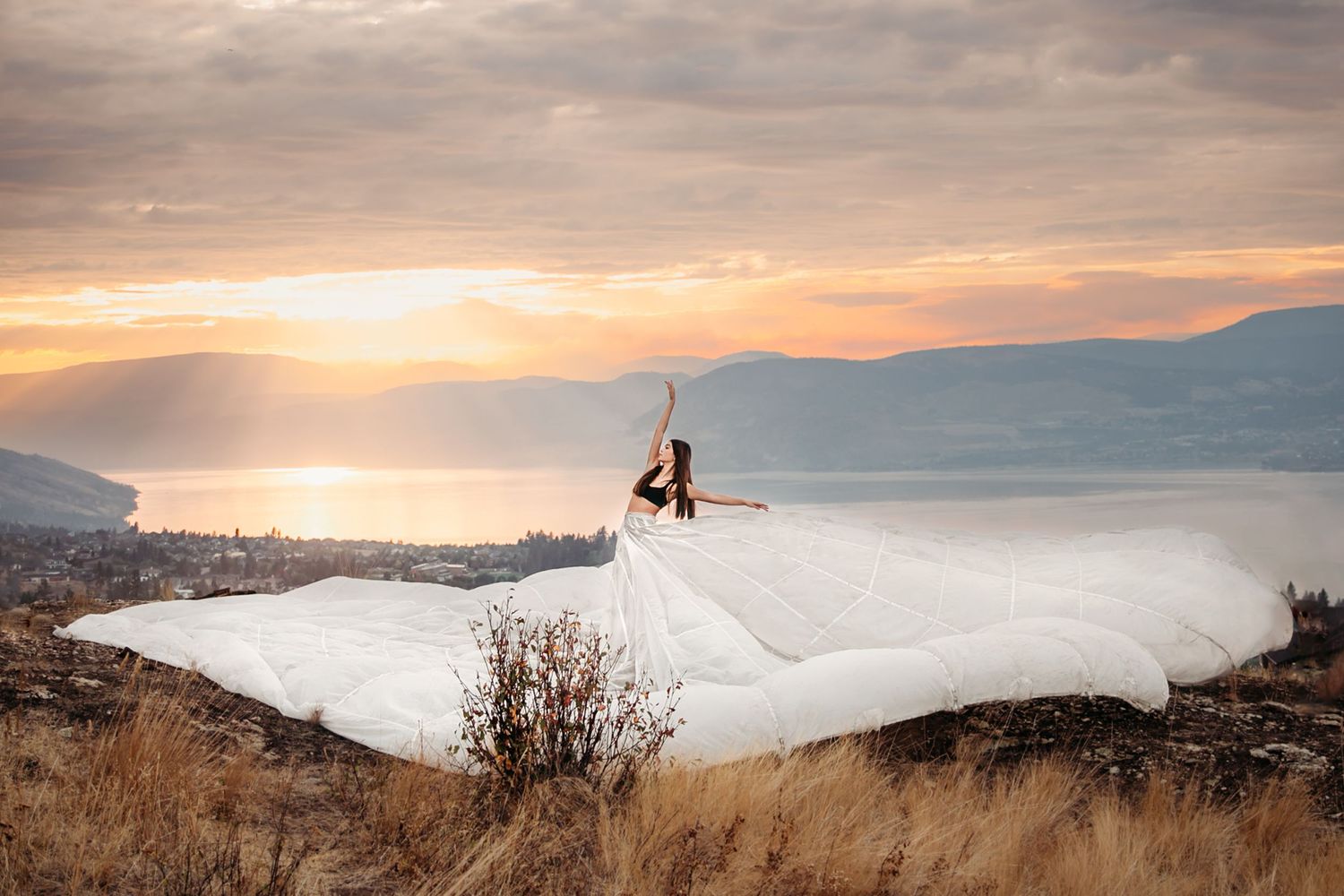 White fabric flowing dramatically on hilltop during golden hour with mountain vista.
