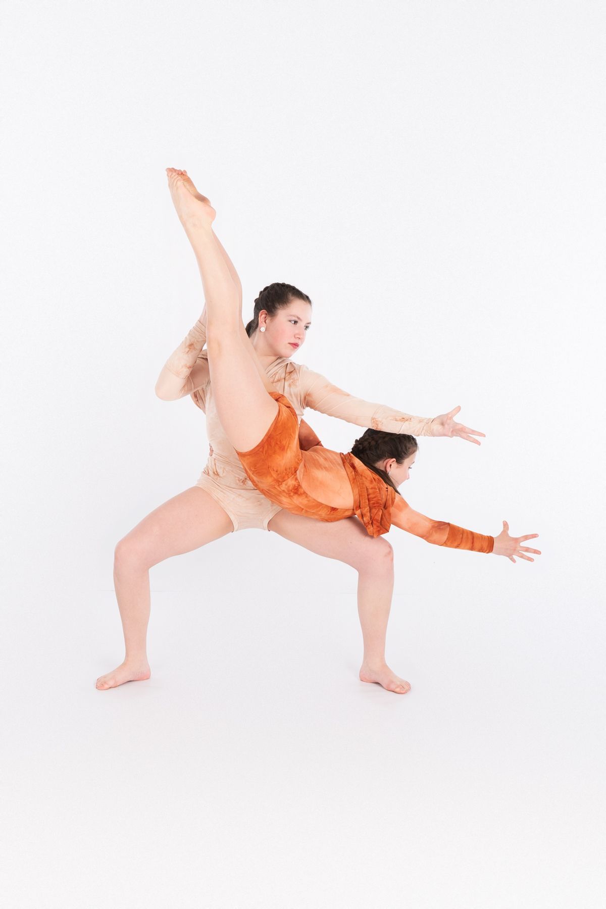 Dancer in orange costume performs dynamic modern dance pose with extended limbs against white background.