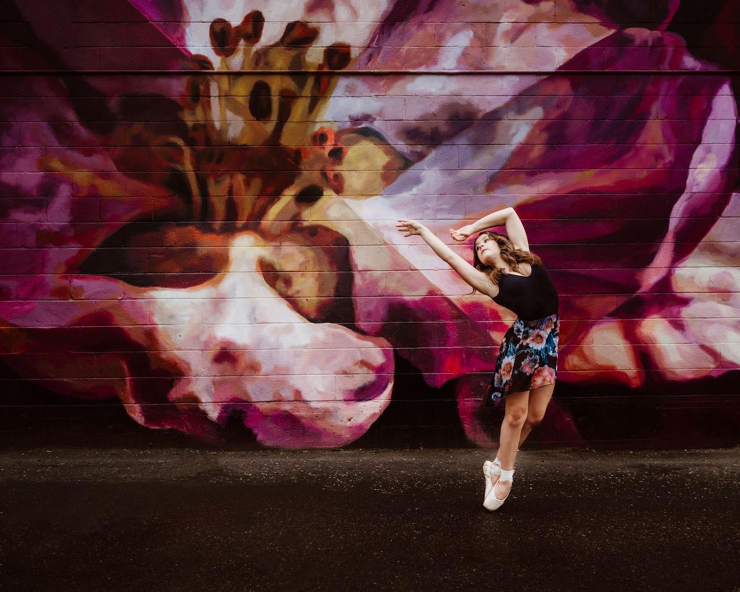 Dancer performs an elegant leap against a vibrant pink floral mural backdrop.