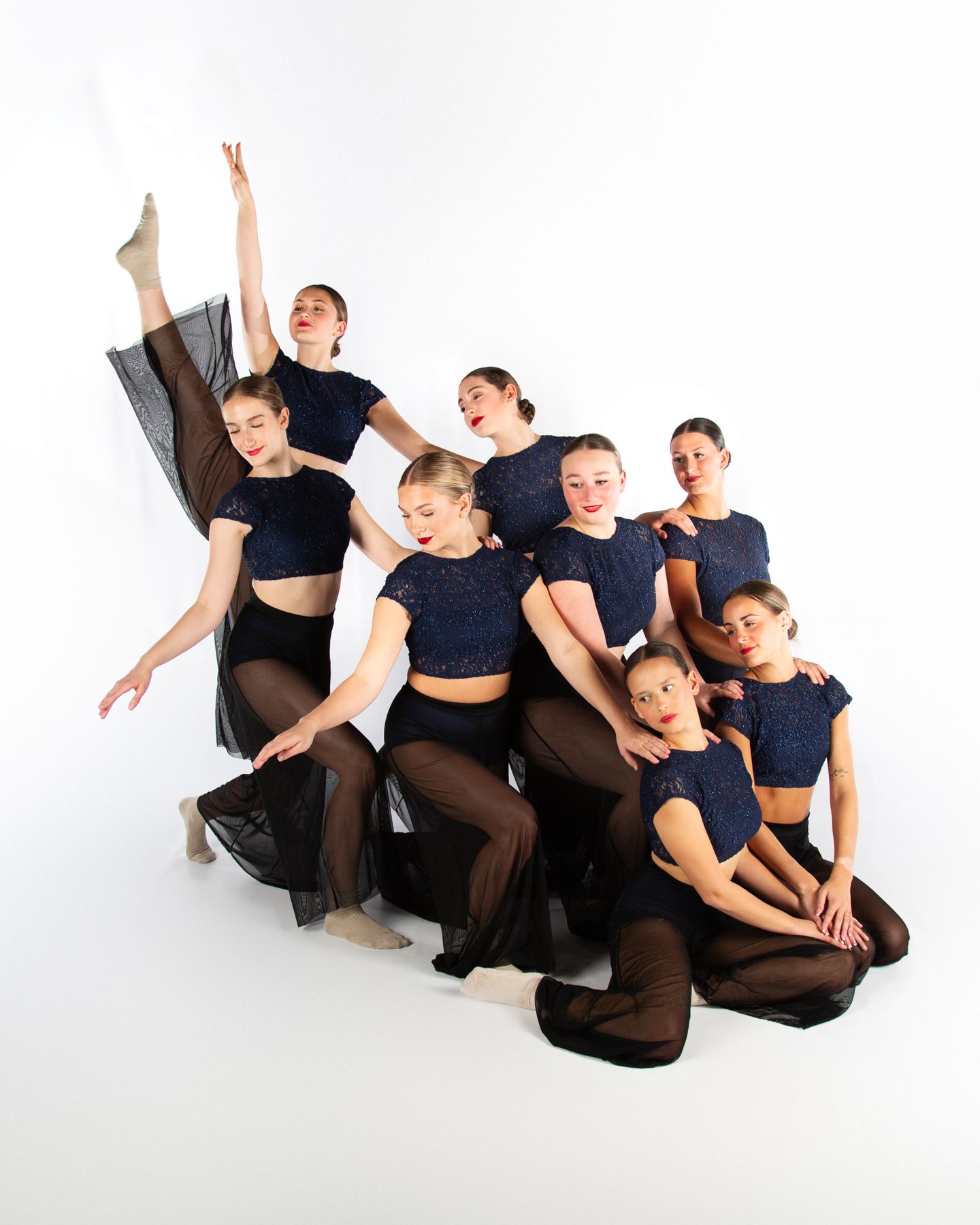 Modern dance group in black and brown costumes performing dynamic contemporary choreography.
