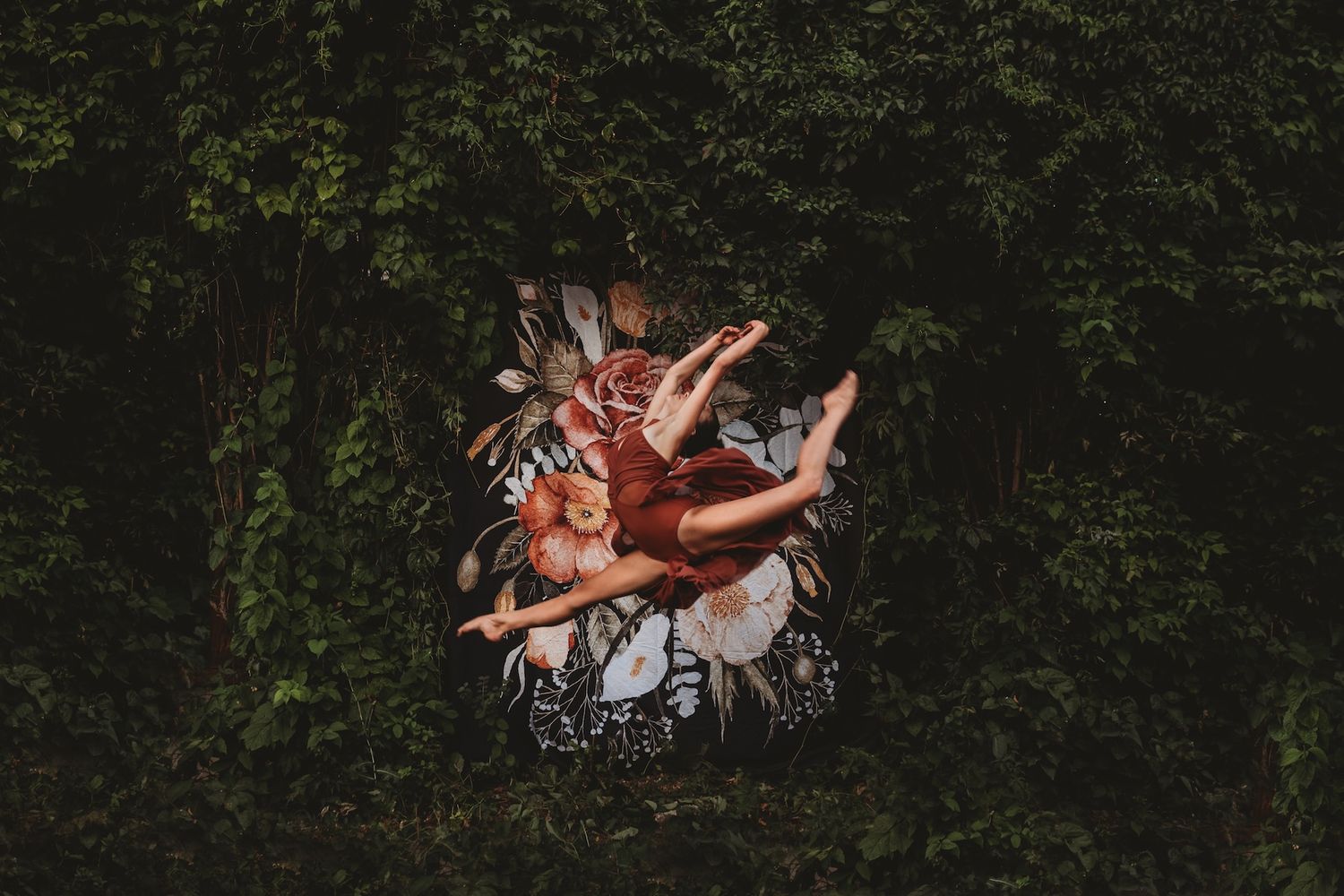 Multiple hands reach upward in a dramatic silhouette against a dark forest background.