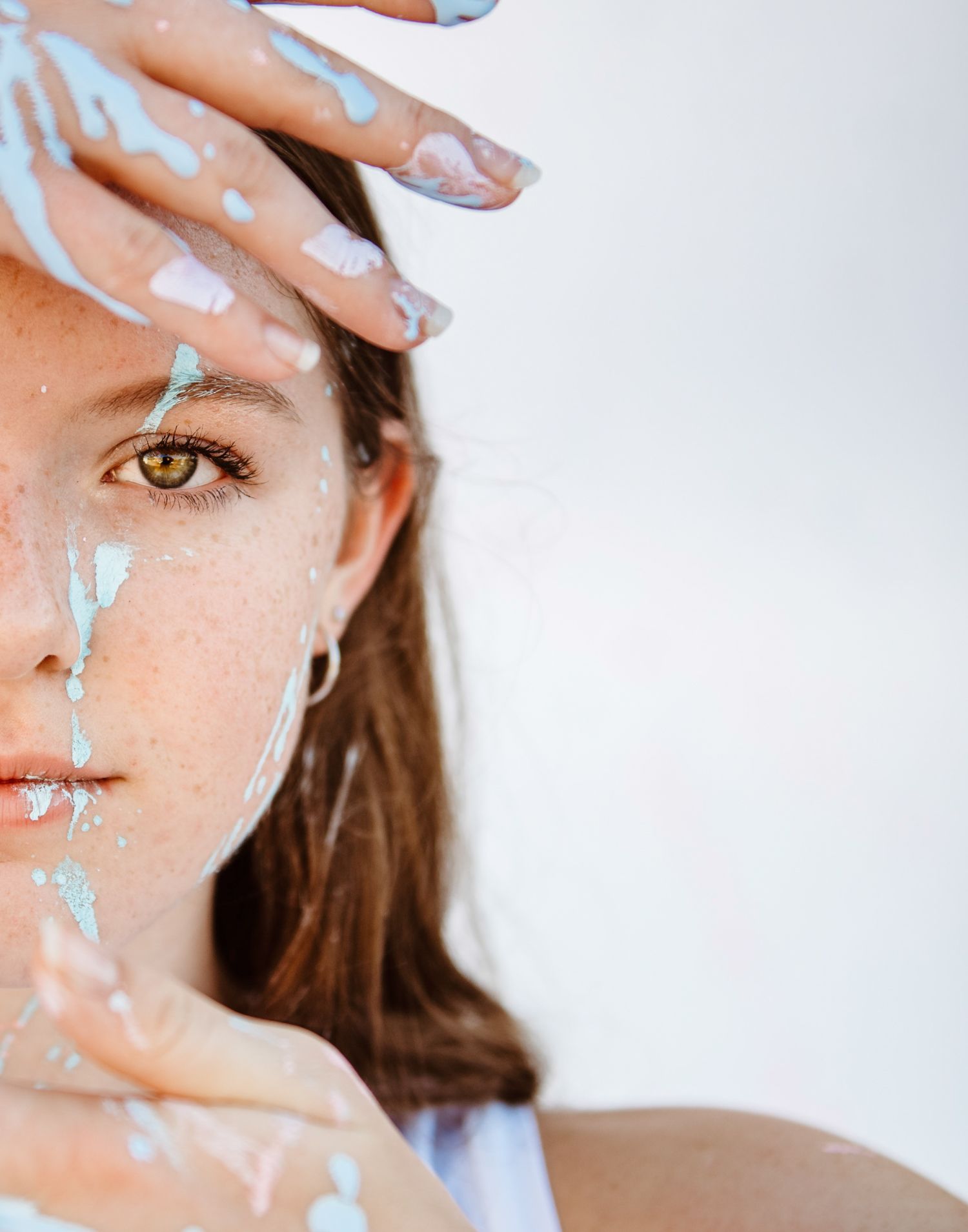 Artistic beauty portrait showing half a face painted with light blue dots against a white background.