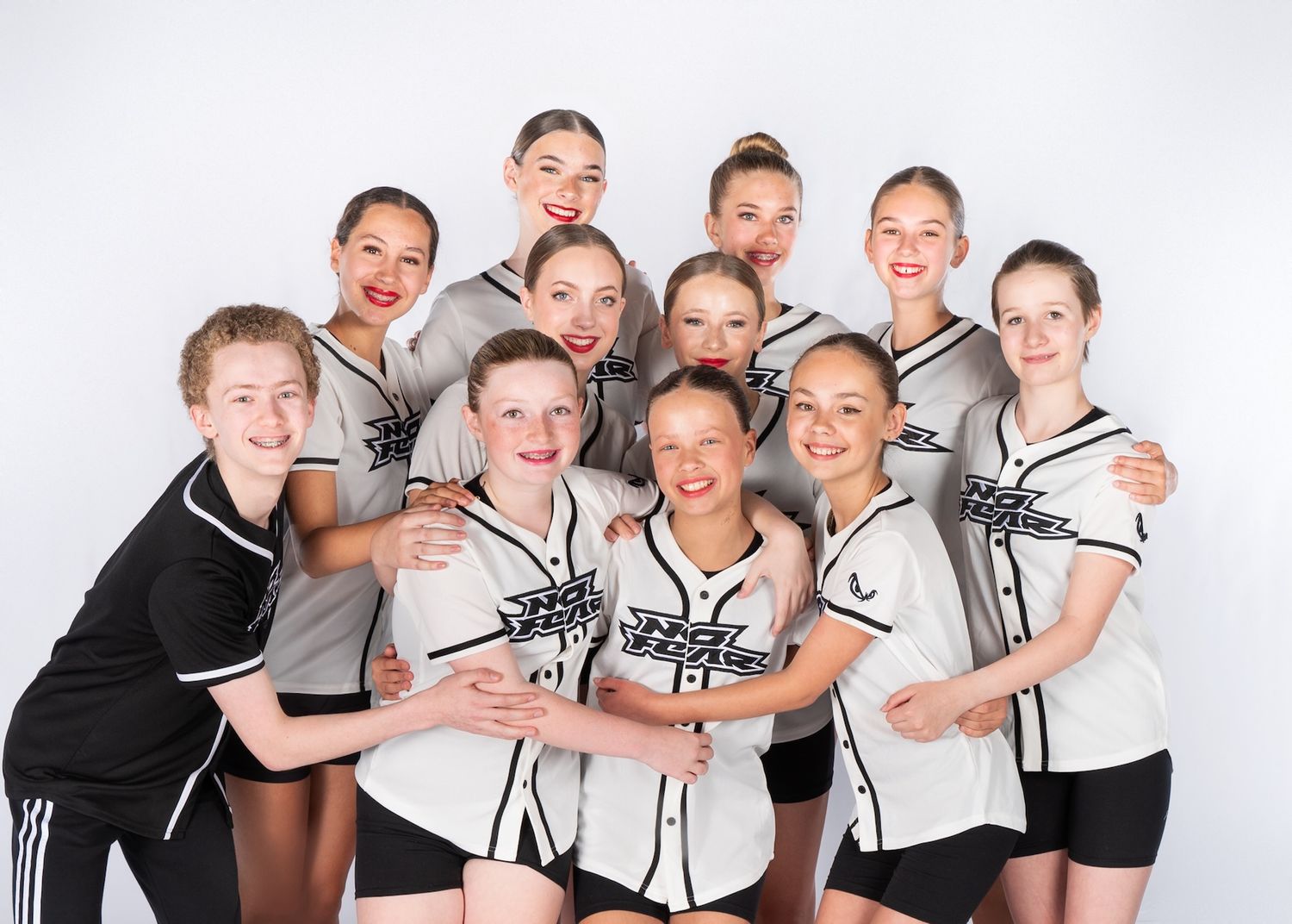 A cheerleading squad in black and white uniforms poses together for a team photo against a light background.