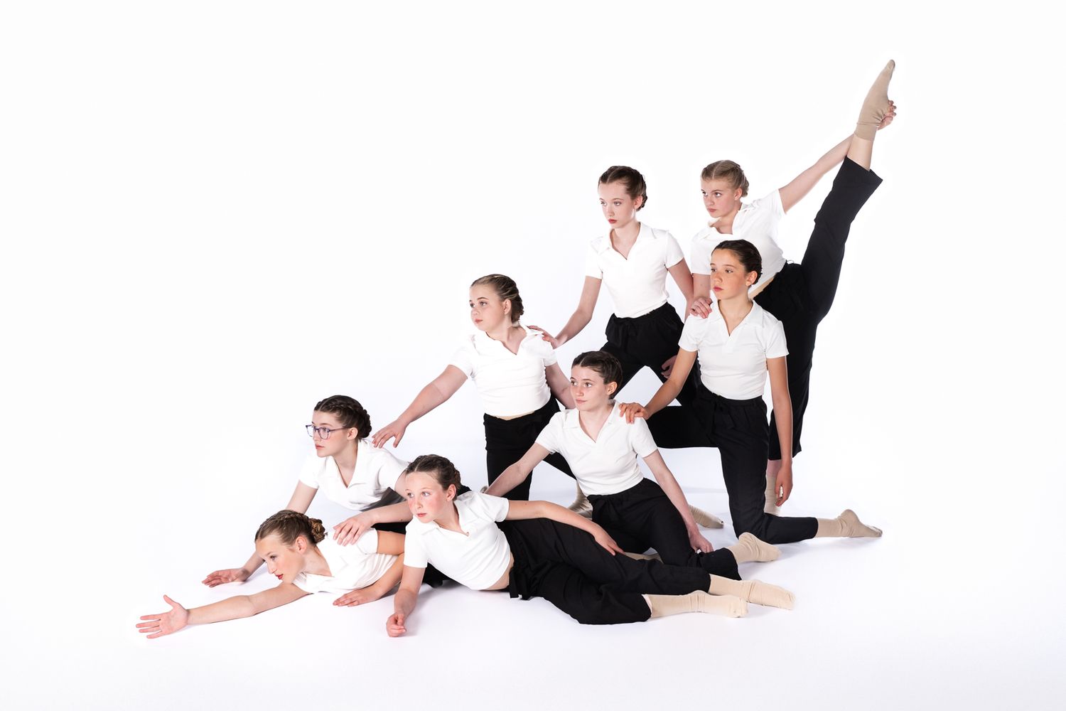 Dance performers in black and white attire creating a dynamic diagonal formation against a white background.