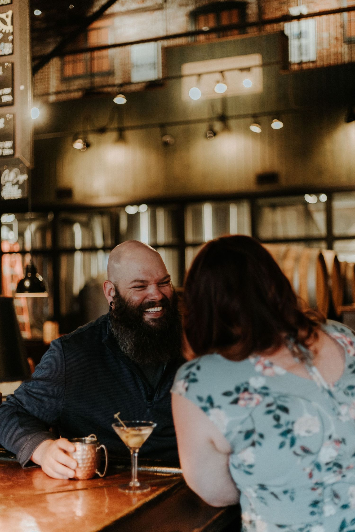 People enjoying drinks and conversation at a dimly lit restaurant bar.