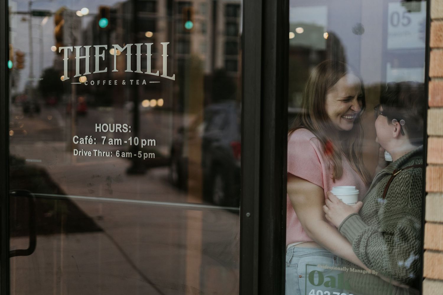 A modern restaurant window displays 'THE MILL' text signage and business hours in white lettering.