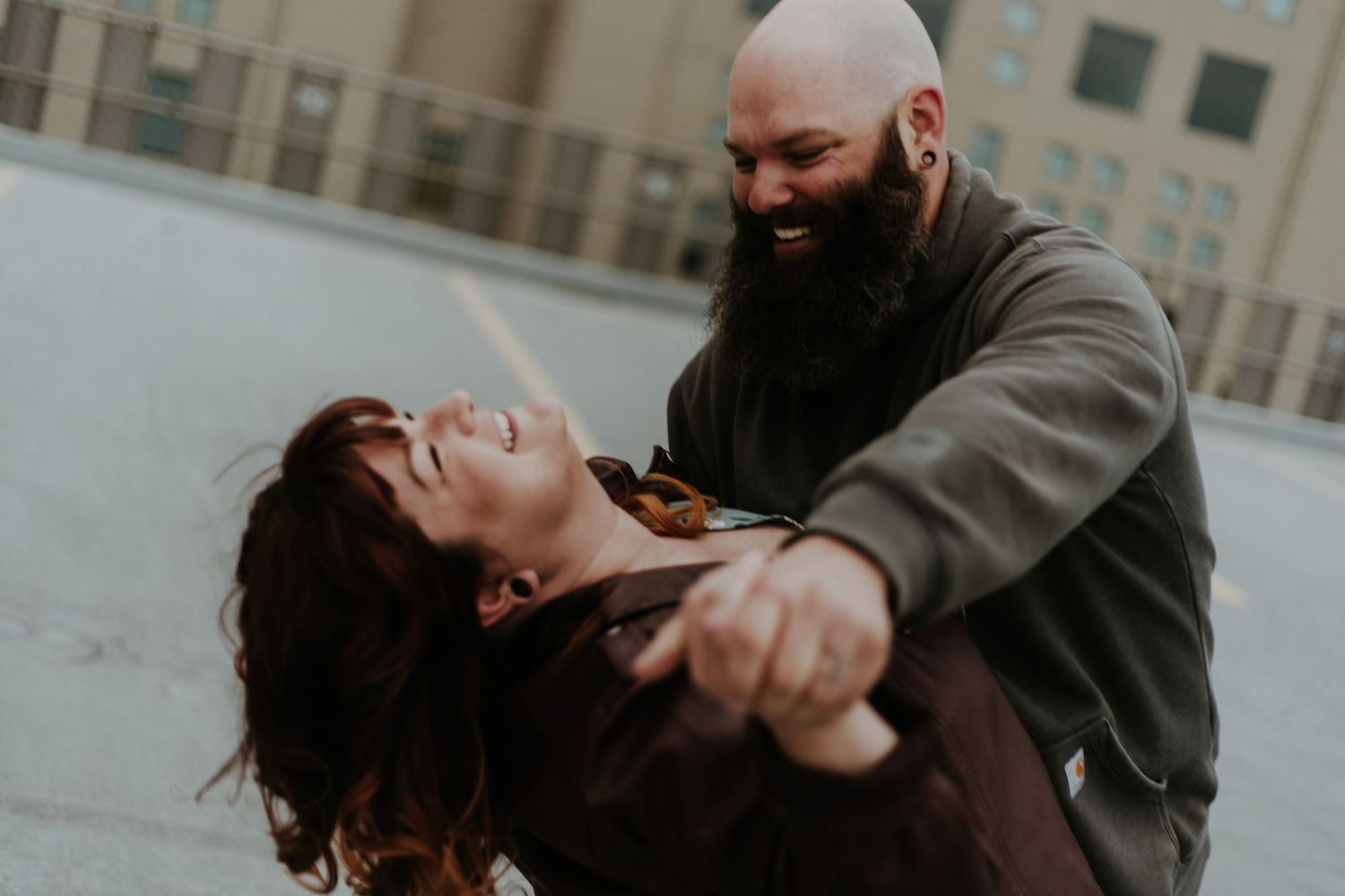 A couple laughs together during a romantic moment on an urban rooftop.