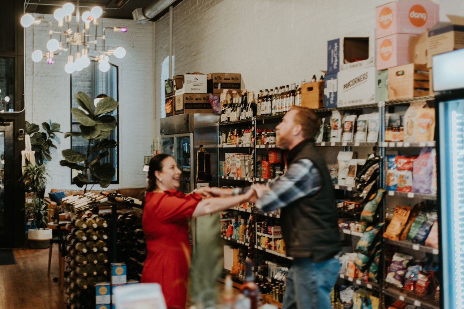 Interior view of a wine shop with wooden shelves stocked with bottles and customers browsing the selection.