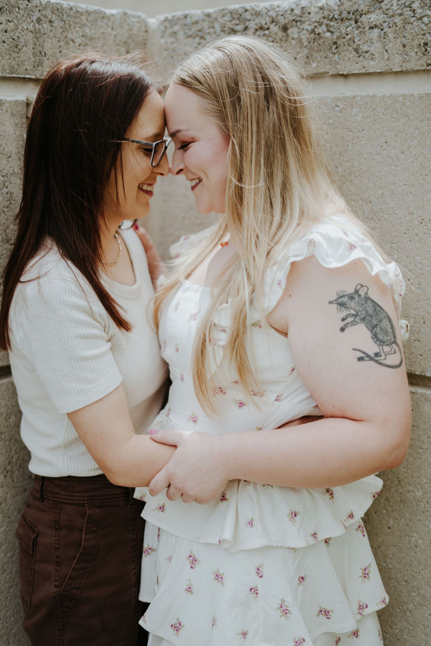 A couple in white and brown outfits sharing intimate moments against a neutral wall in a series of connected photos.