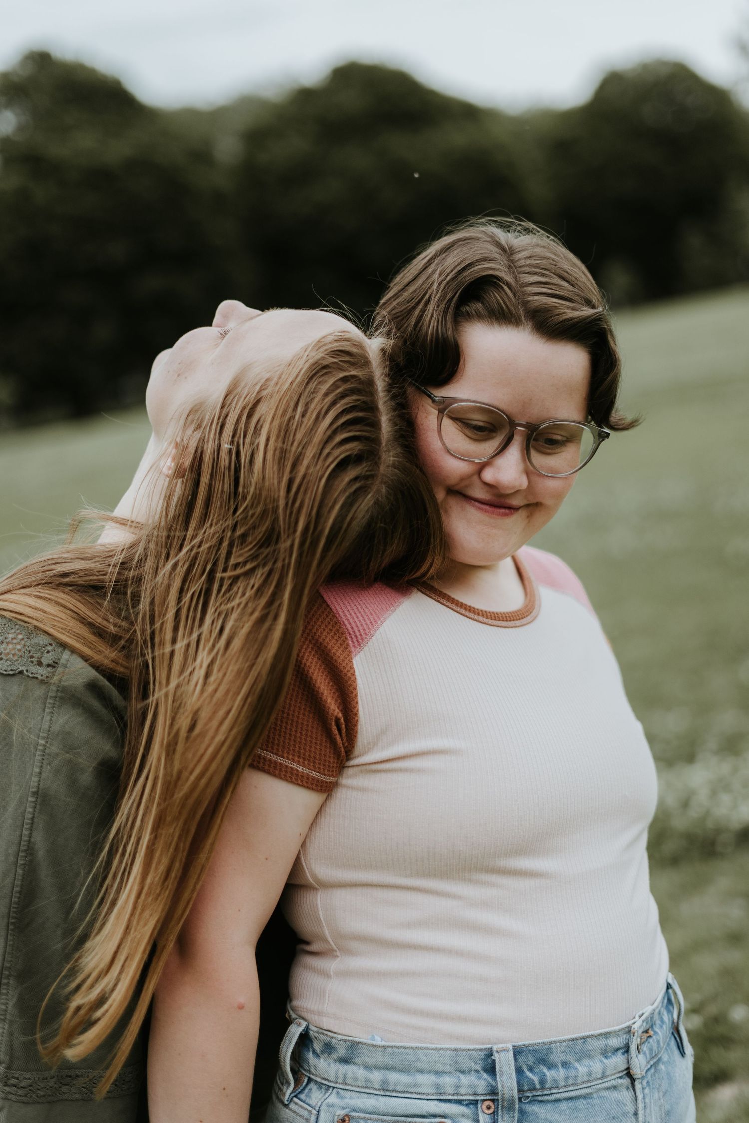 Two people embrace in a tender moment outdoors, showing affection and closeness in a natural setting.