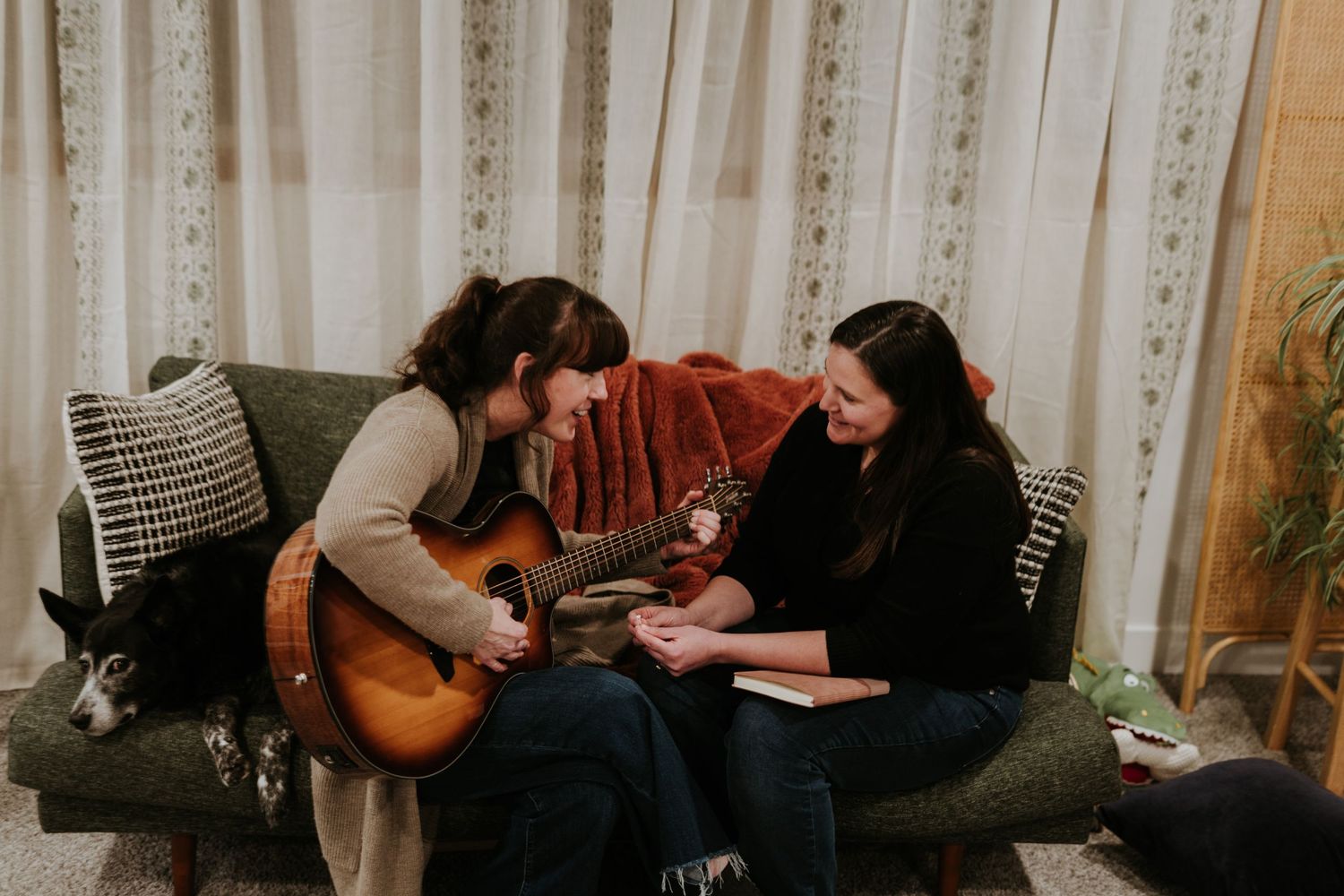A group of musicians sits on a couch during a casual recording session with guitars and other instruments.