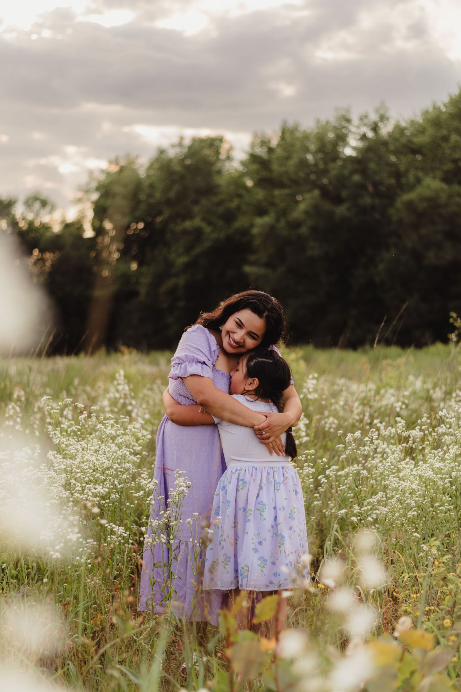 A tender moment captured between two people embracing in a field of wildflowers at sunset.