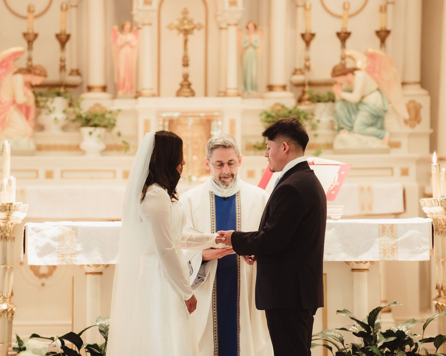 Exchanging vows at a church altar with a priest officiating during a traditional wedding ceremony at St. Lawrence in Lafayette, Indiana.