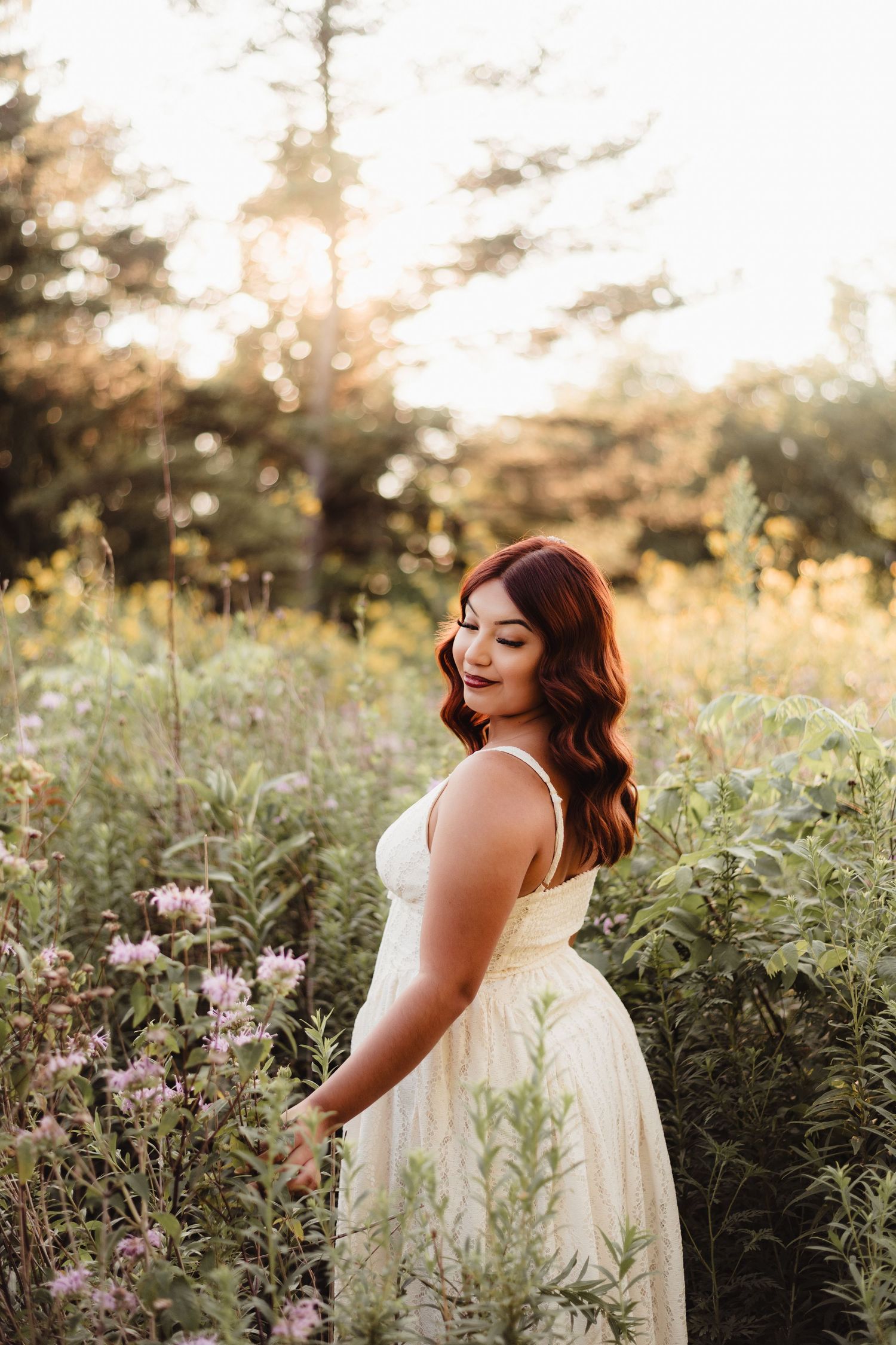 Woman in white dress standing in wildflower field at golden hour sunset in Lafayette, indiana.