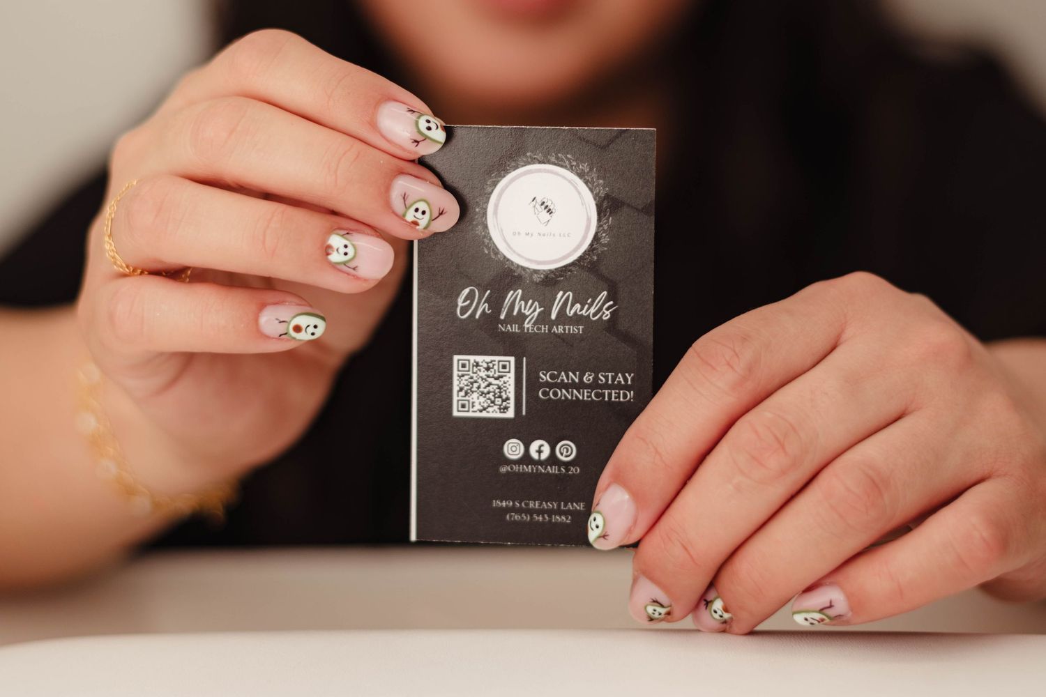Woman holding Oh Hey Nails business card with QR code, showcasing elegant nail art design.