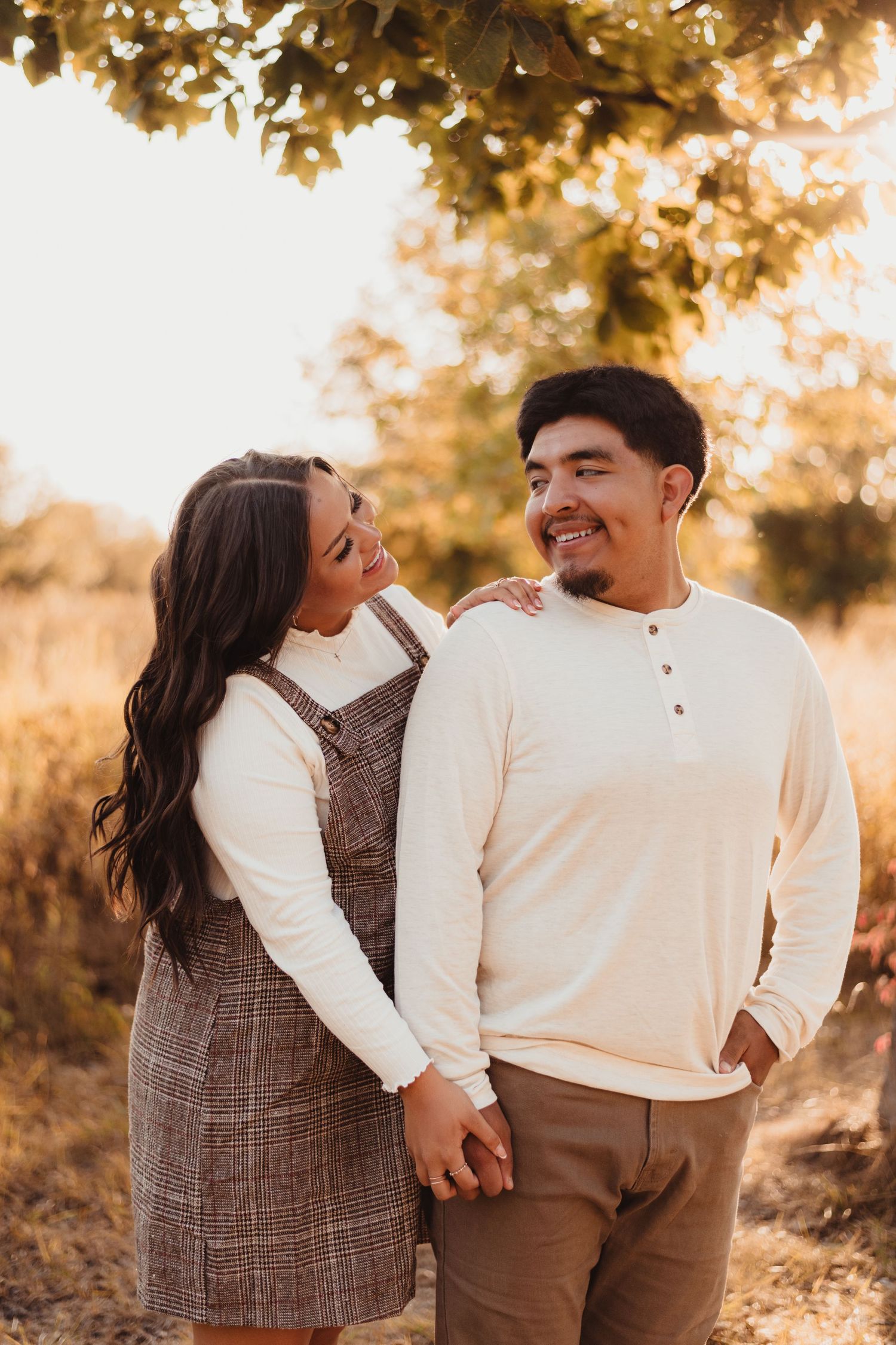 A couple shares a romantic moment in autumn sunlight while wearing casual attire.