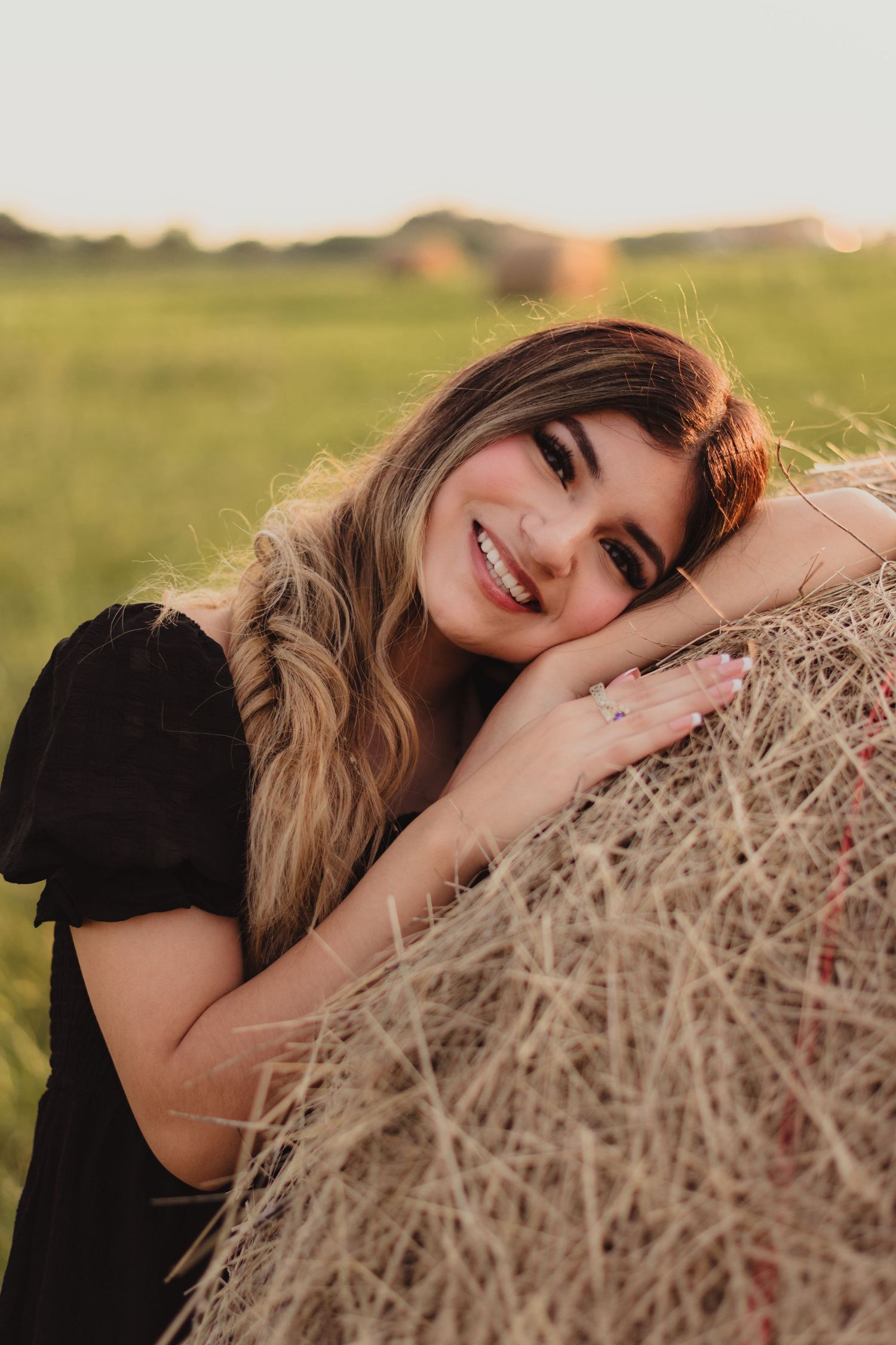 A series of portraits showing someone posing playfully with a hay bale in a sunny field at golden hour.